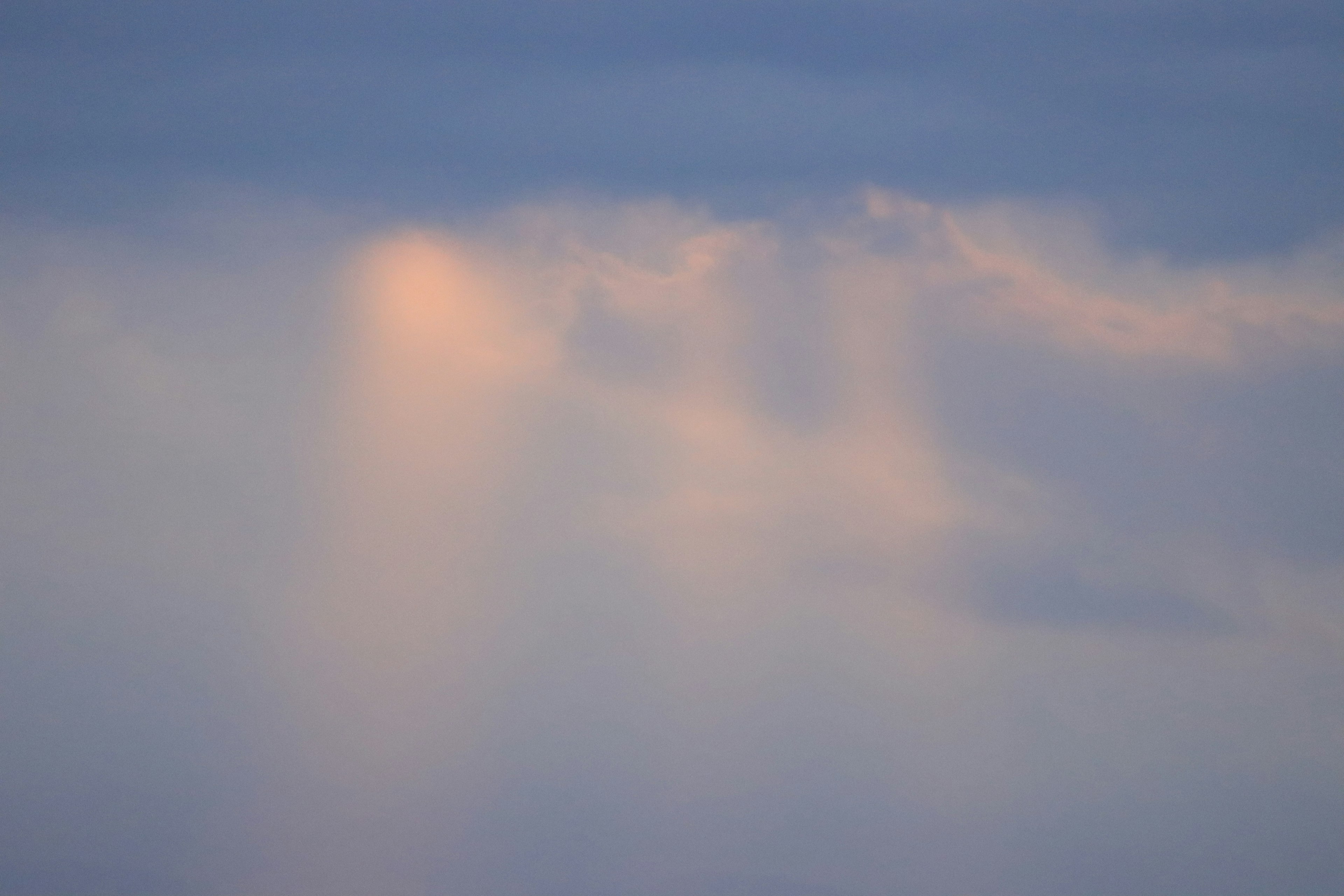 Awan lembut yang diterangi cahaya di latar belakang langit biru