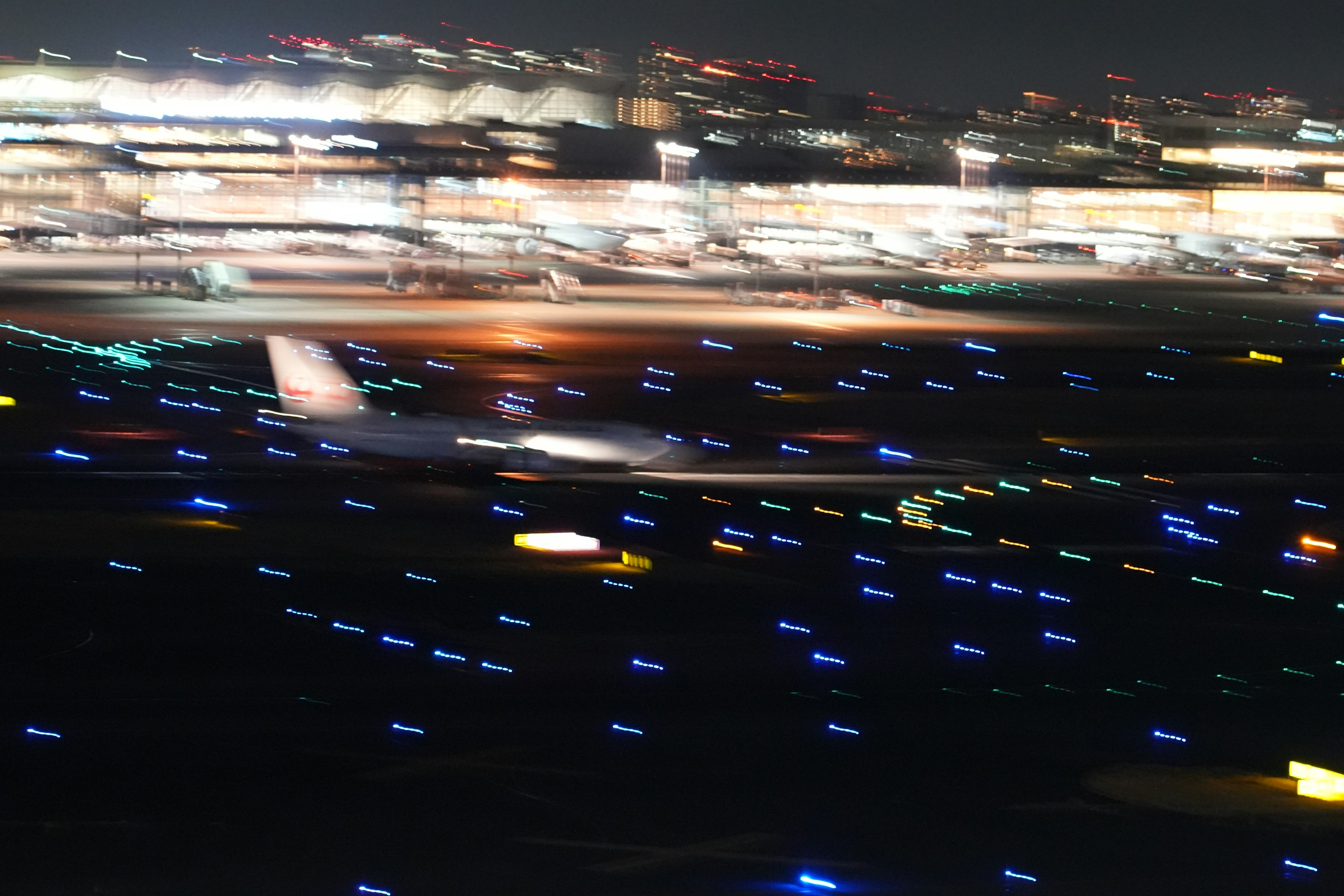 Airplane landing on a runway at night with illuminated taxiway lights