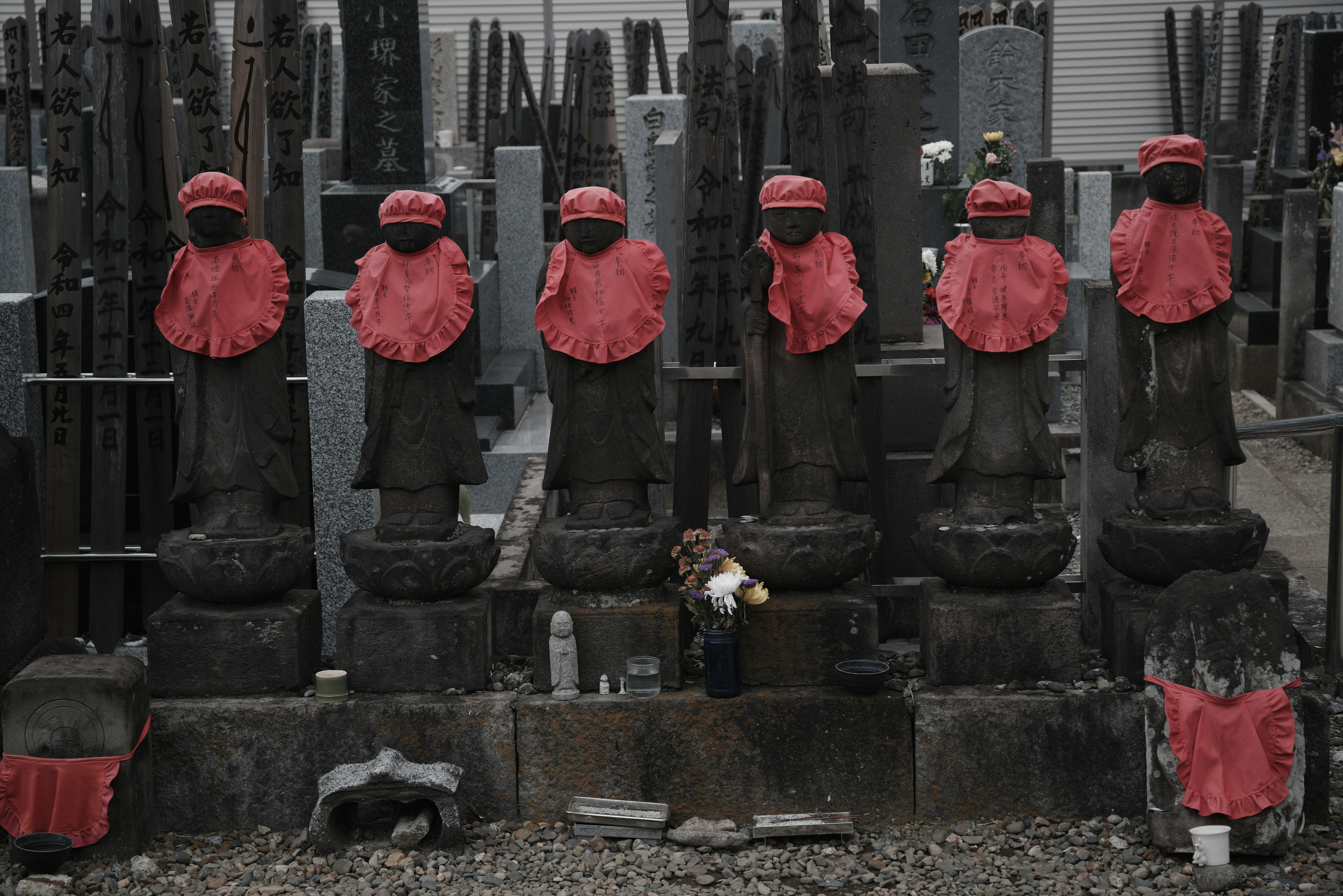 Una escena de cementerio con estatuas de piedra que llevan delantales rojos