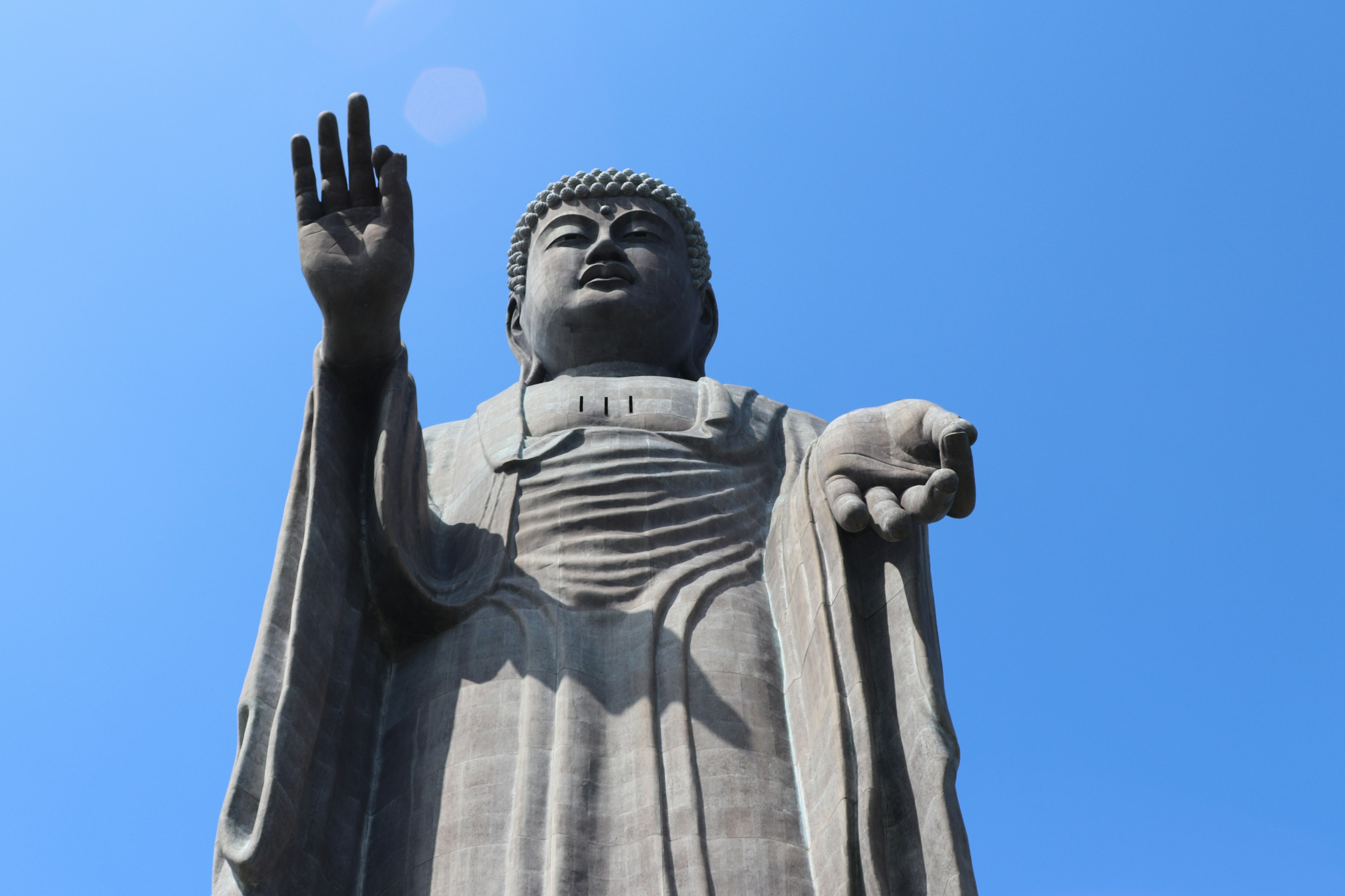 Grande statua del Buddha che si erge sotto un cielo blu chiaro