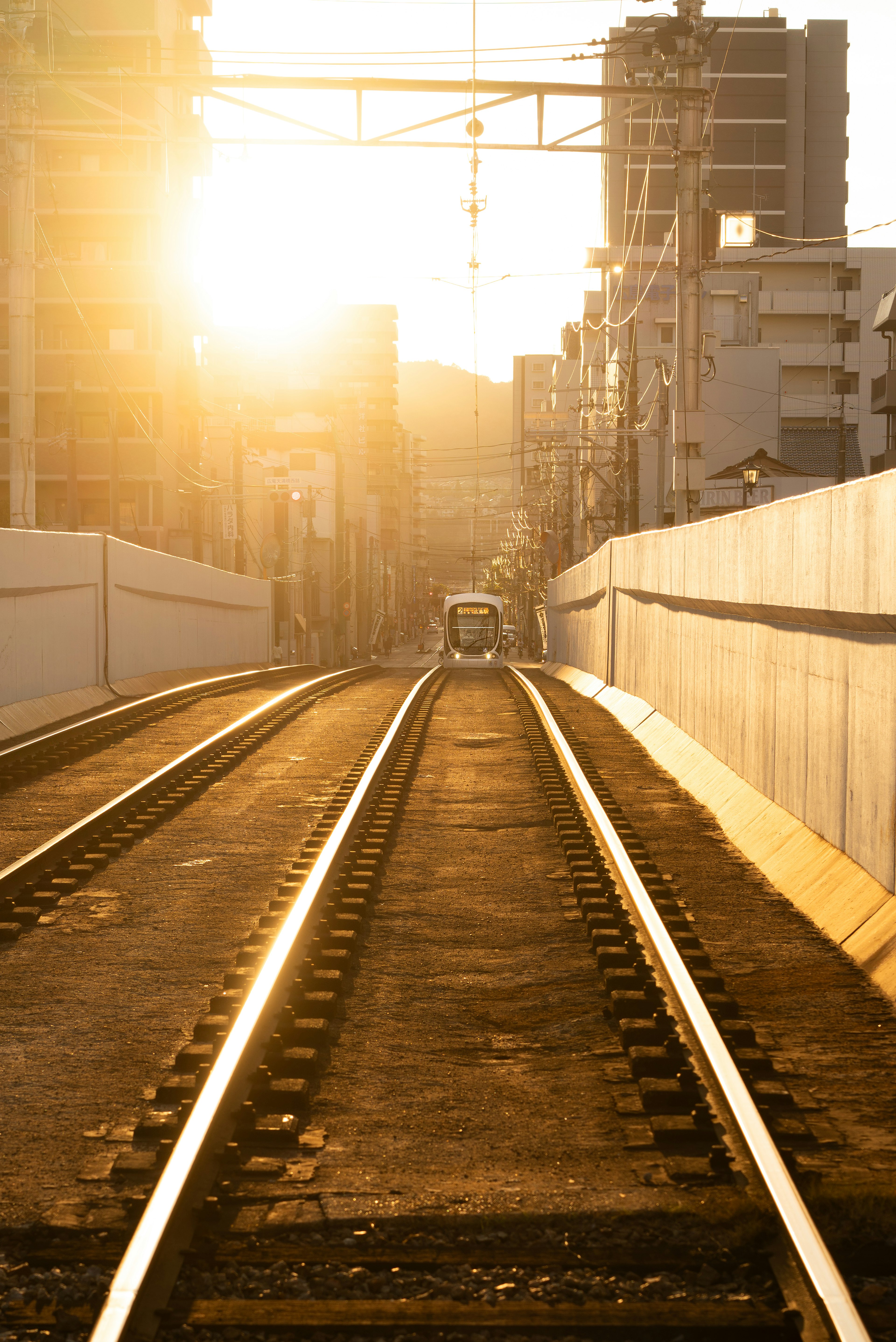 Atardecer iluminando vías de tren con fondo urbano