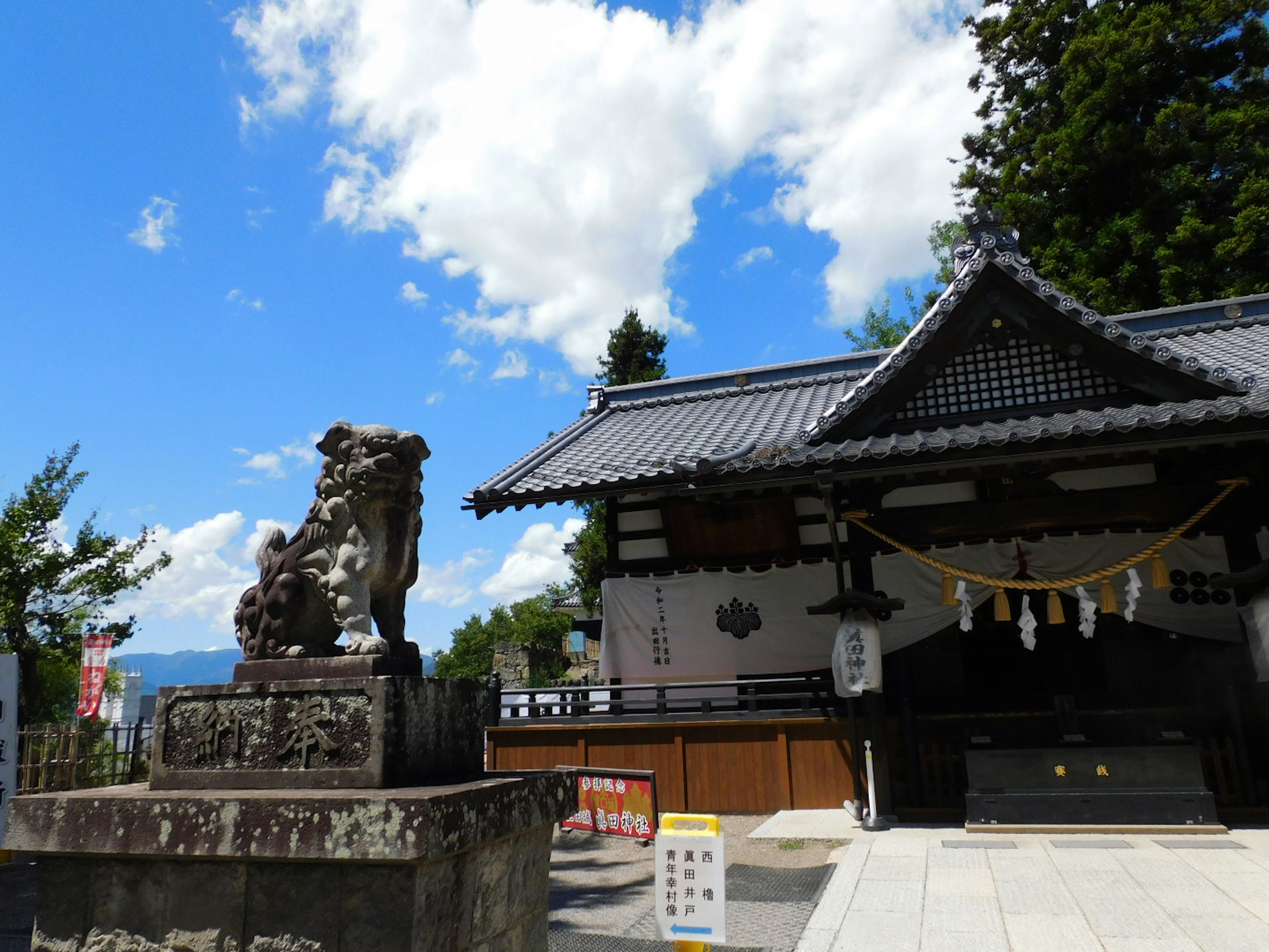 青空の下にある神社の外観と狛犬の像