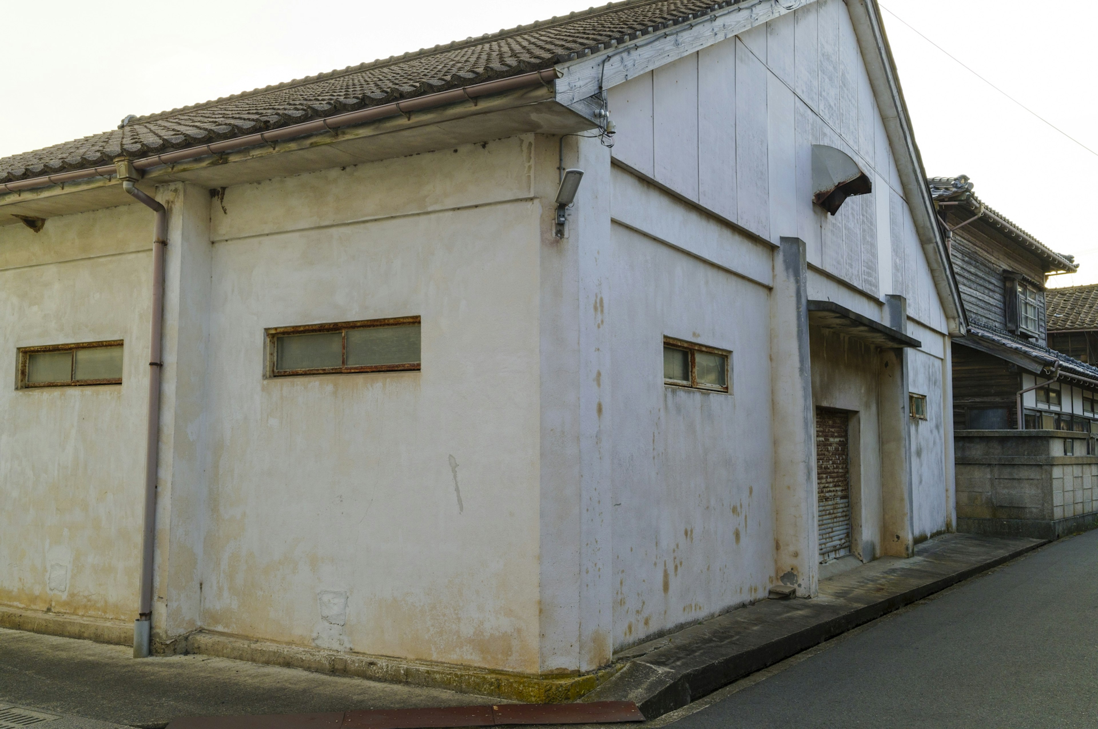 Old white building exterior with small simple windows located on a quiet street