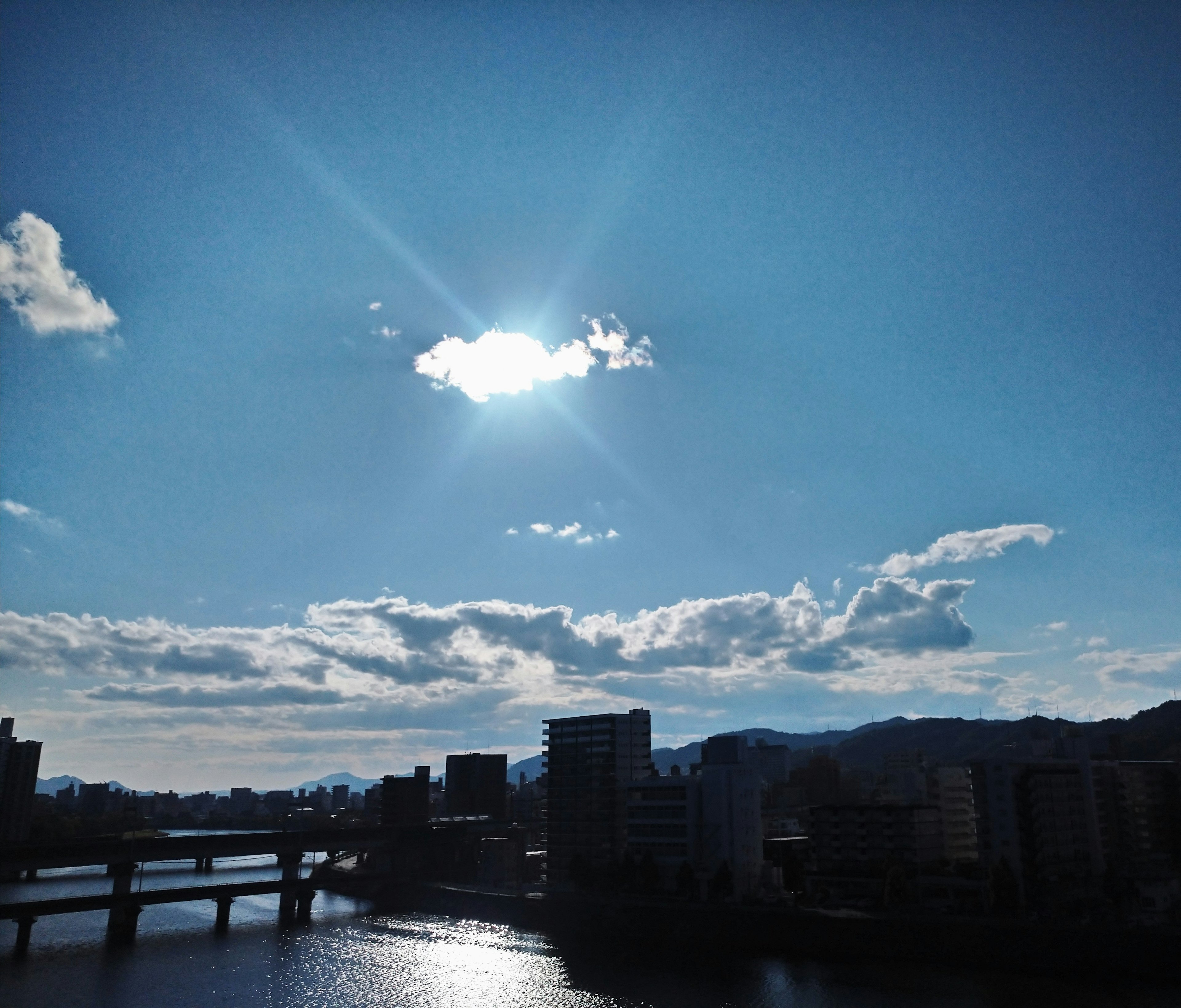 Una vista escénica de un río que refleja la luz del sol bajo un cielo azul parcialmente nublado