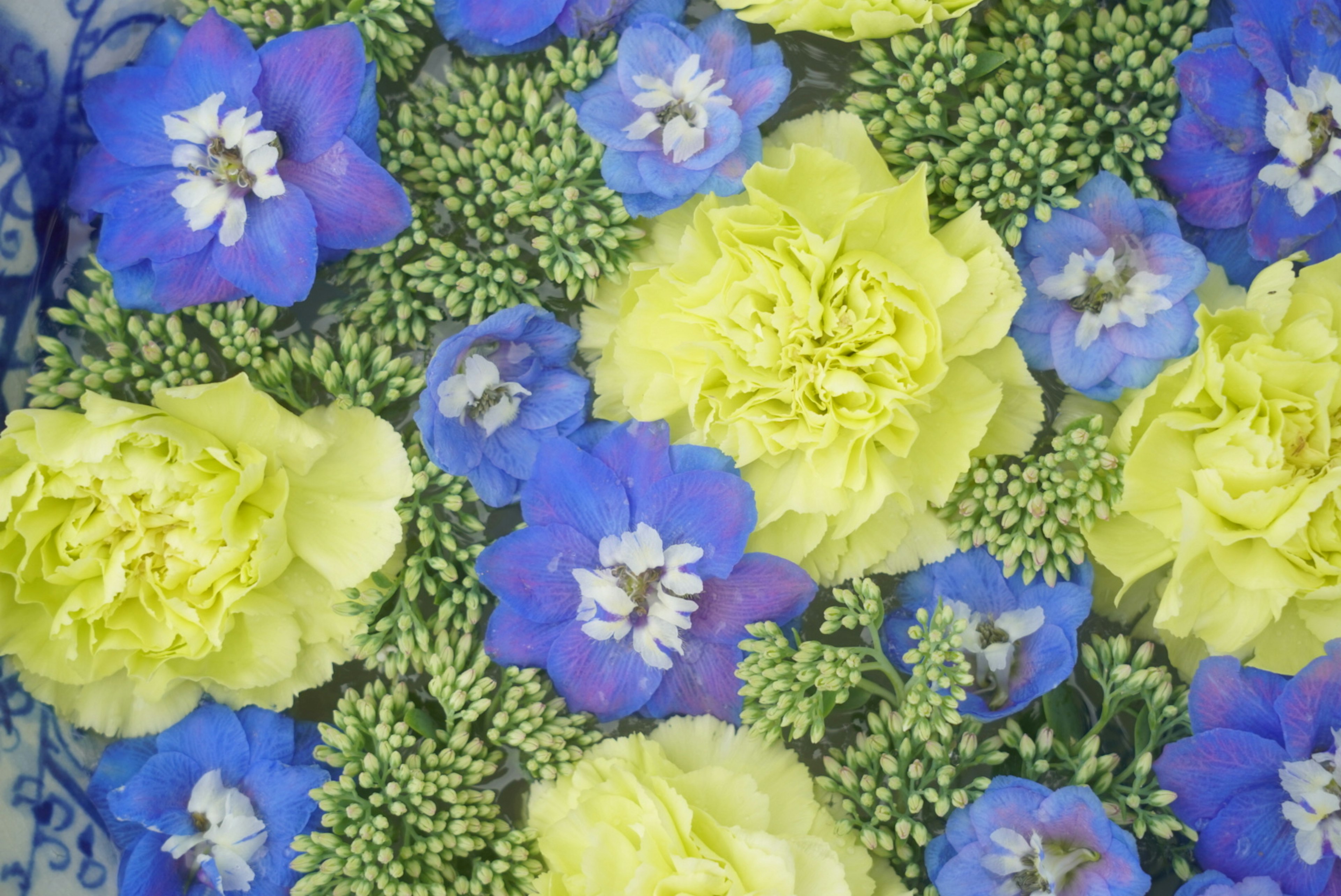 Beautiful arrangement of colorful flowers featuring yellow carnations and blue delphiniums