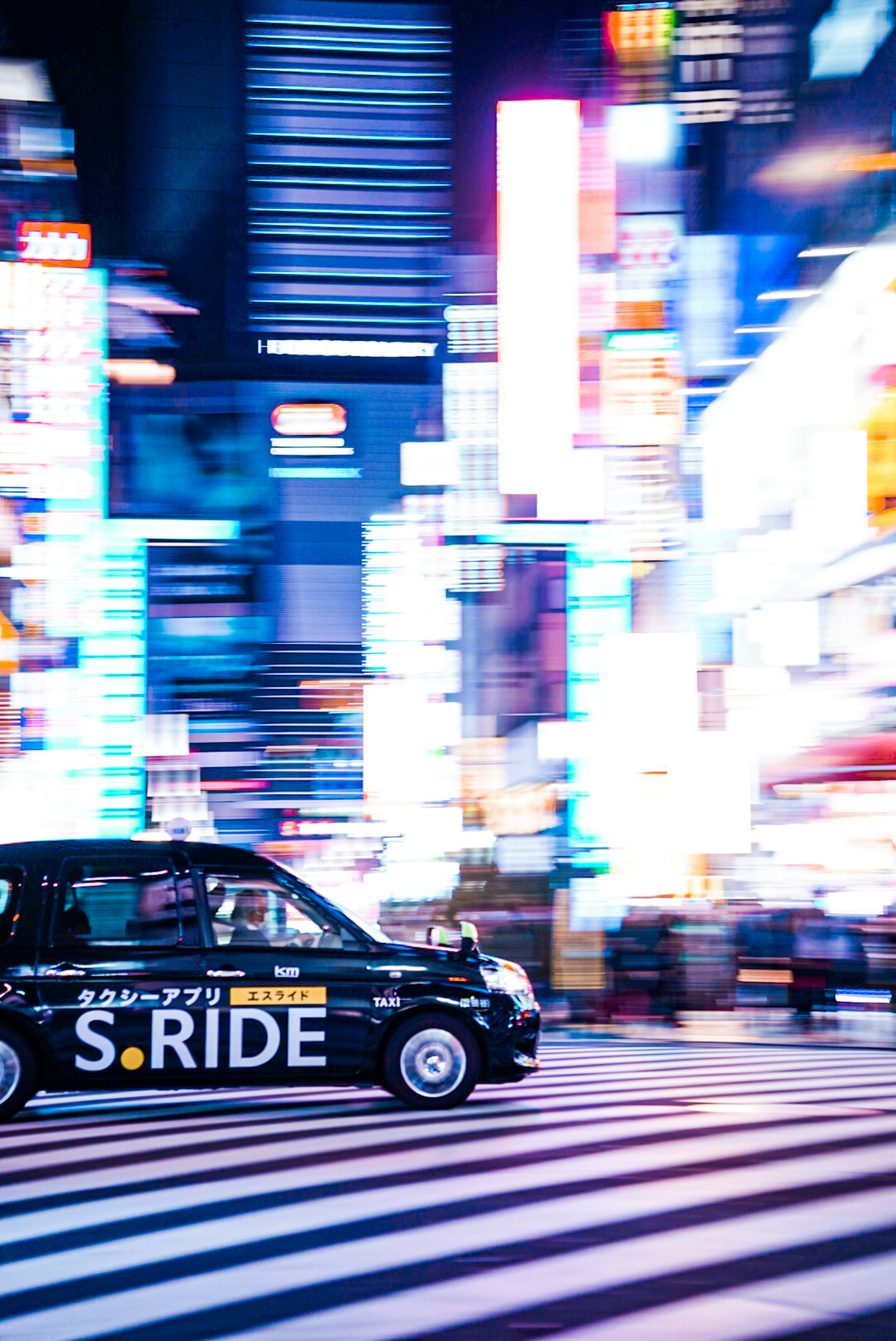 Taxi driving through Tokyo's vibrant streets with bright neon lights at night