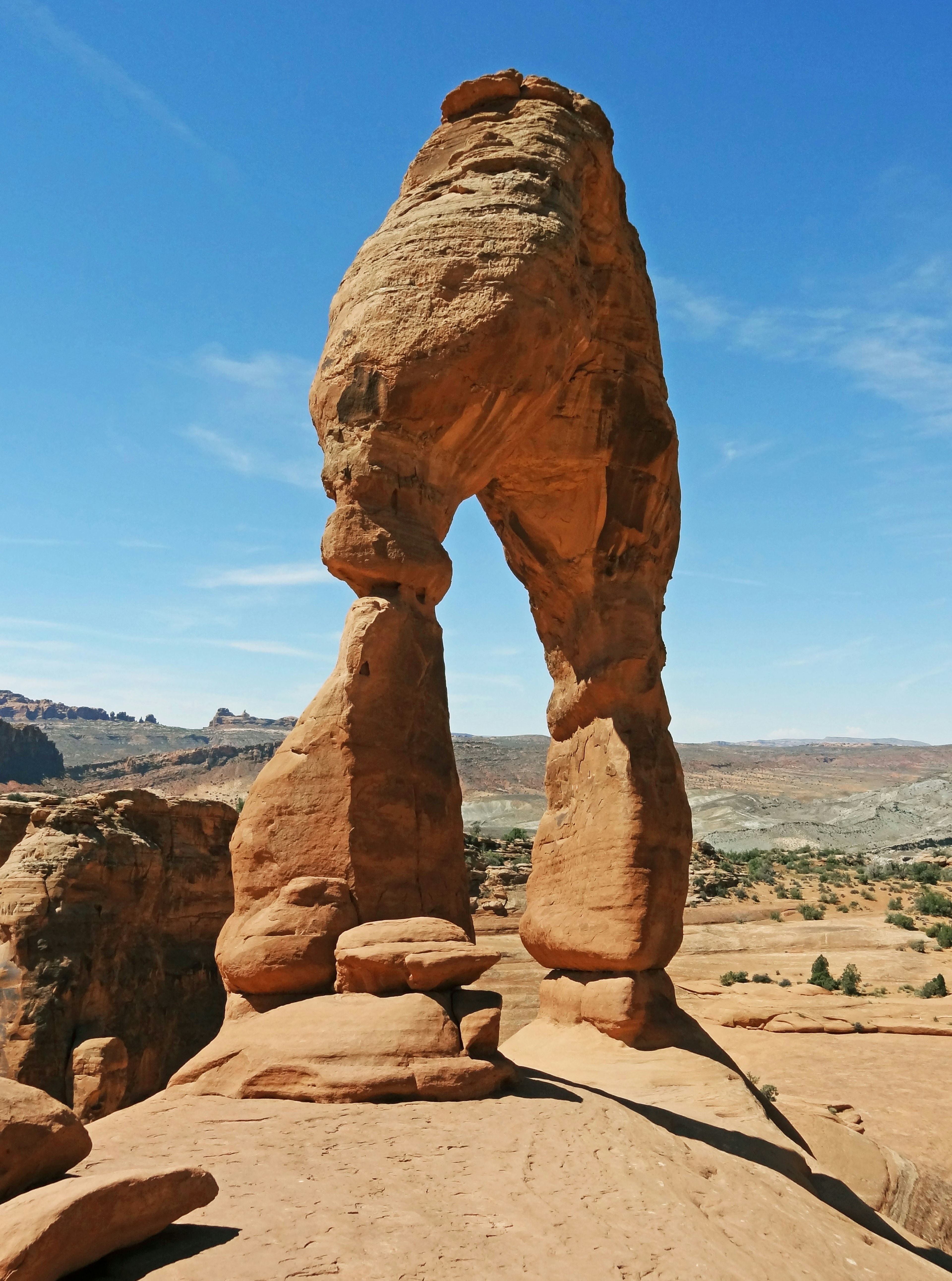 Arco di roccia rossa unico che si erge sotto un cielo blu