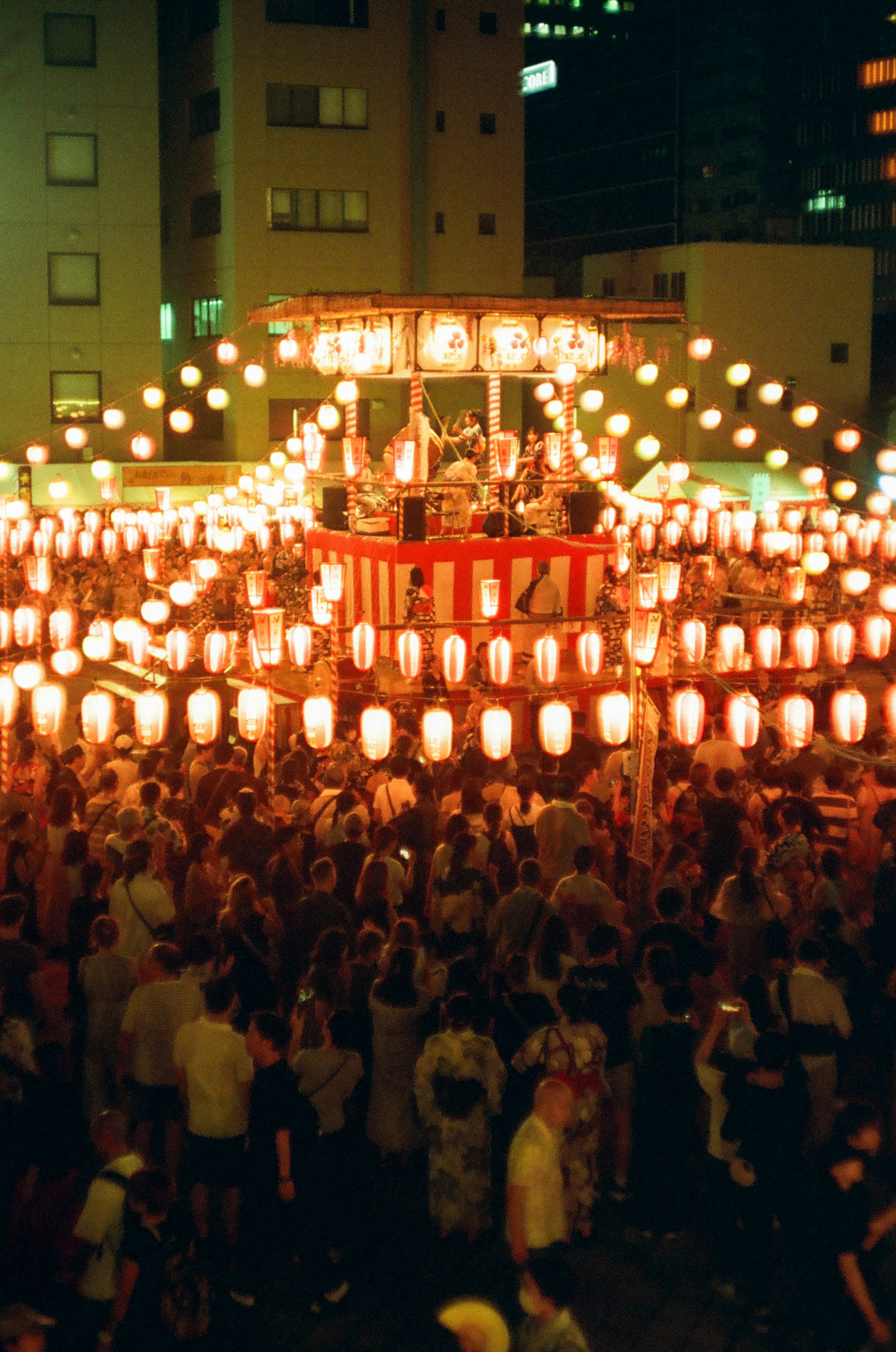 夜の祭りの中で赤い提灯に囲まれた盆踊りの舞台