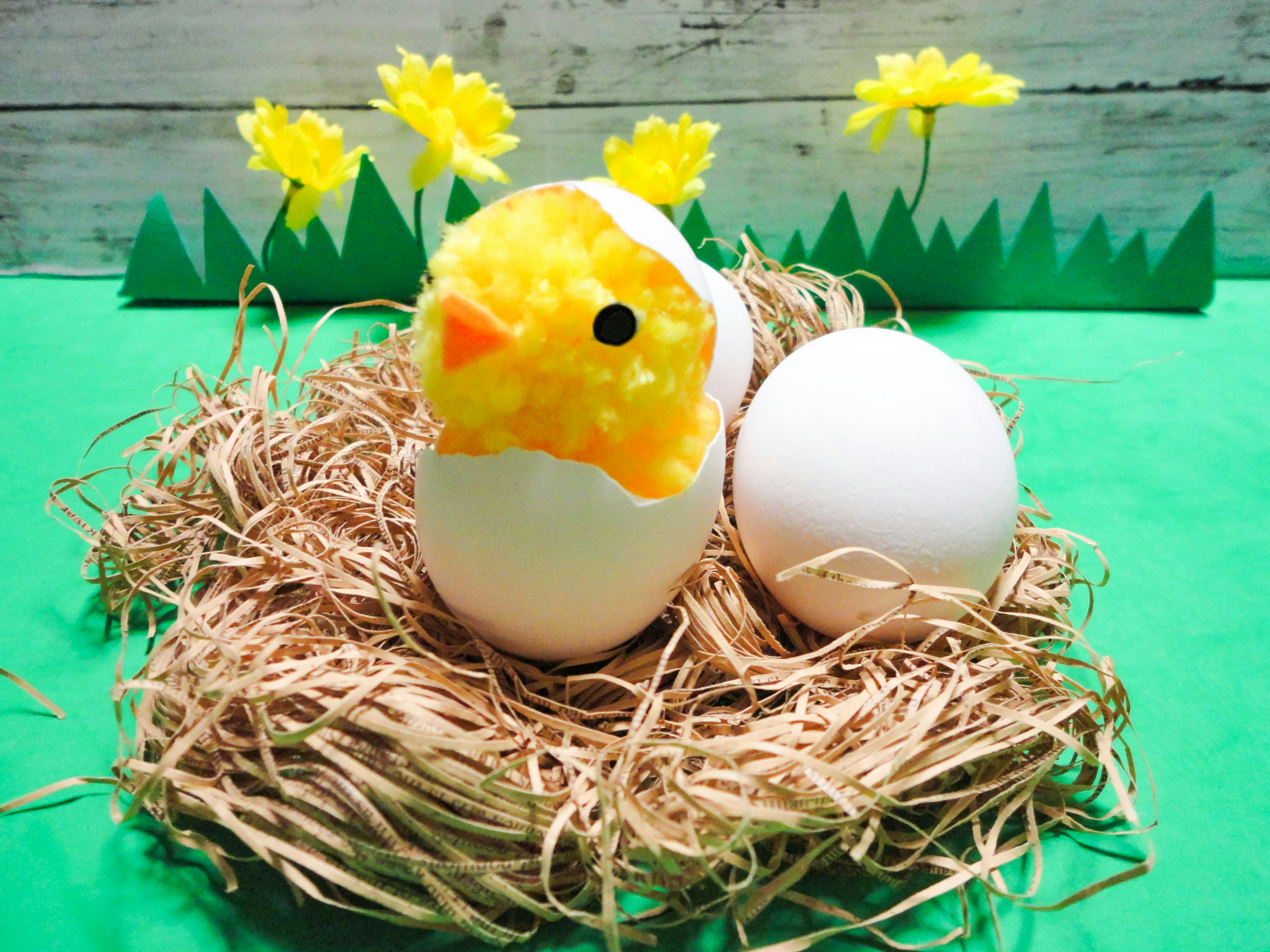 A yellow chick peeking out from an eggshell in a colorful spring scene