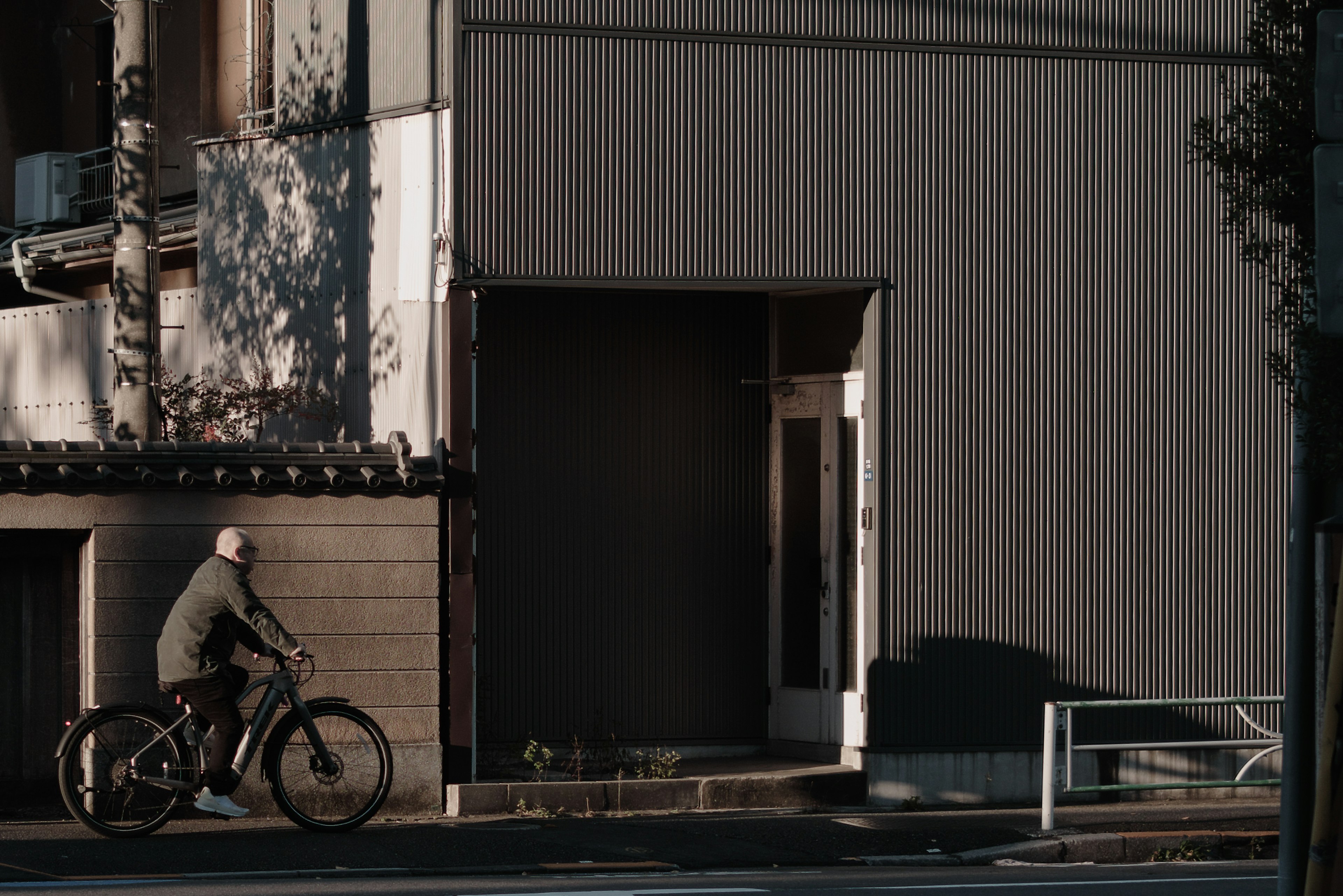 Un homme à vélo passant devant un bâtiment dans une lumière douce du soir