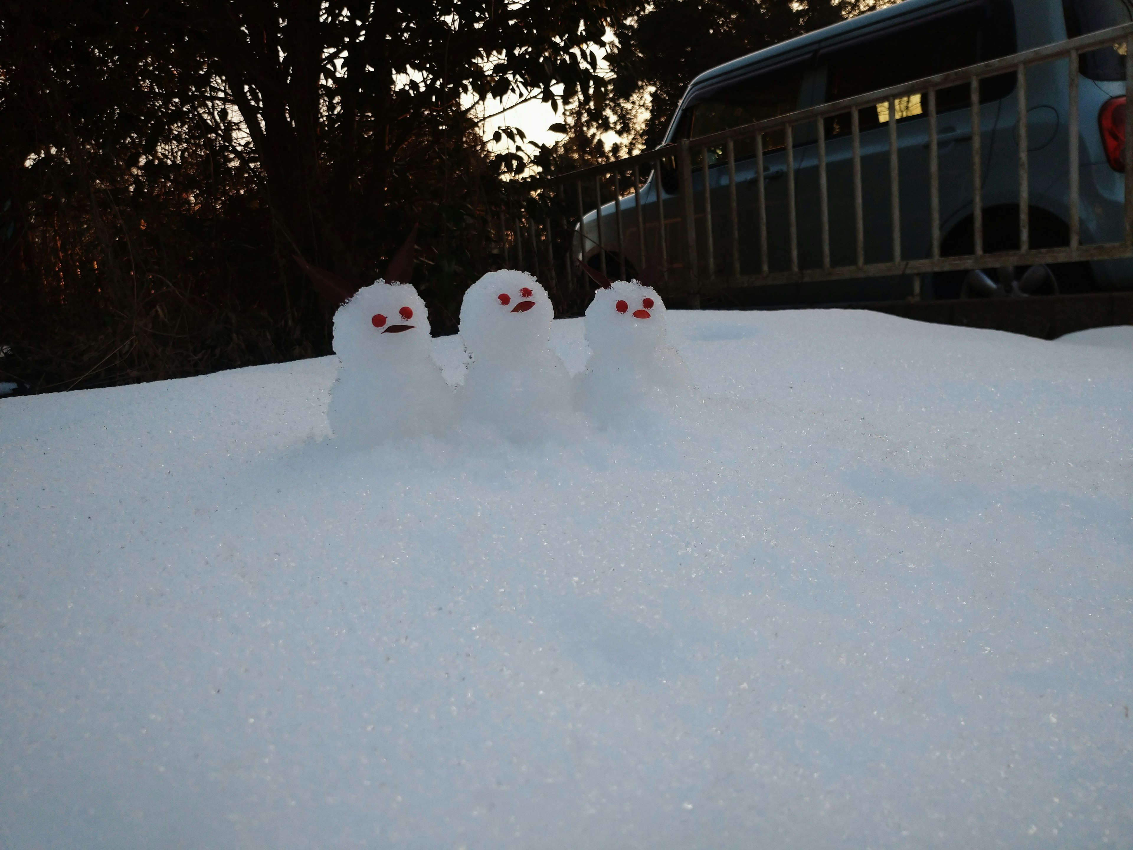 雪の上に立っている三体の雪だるま