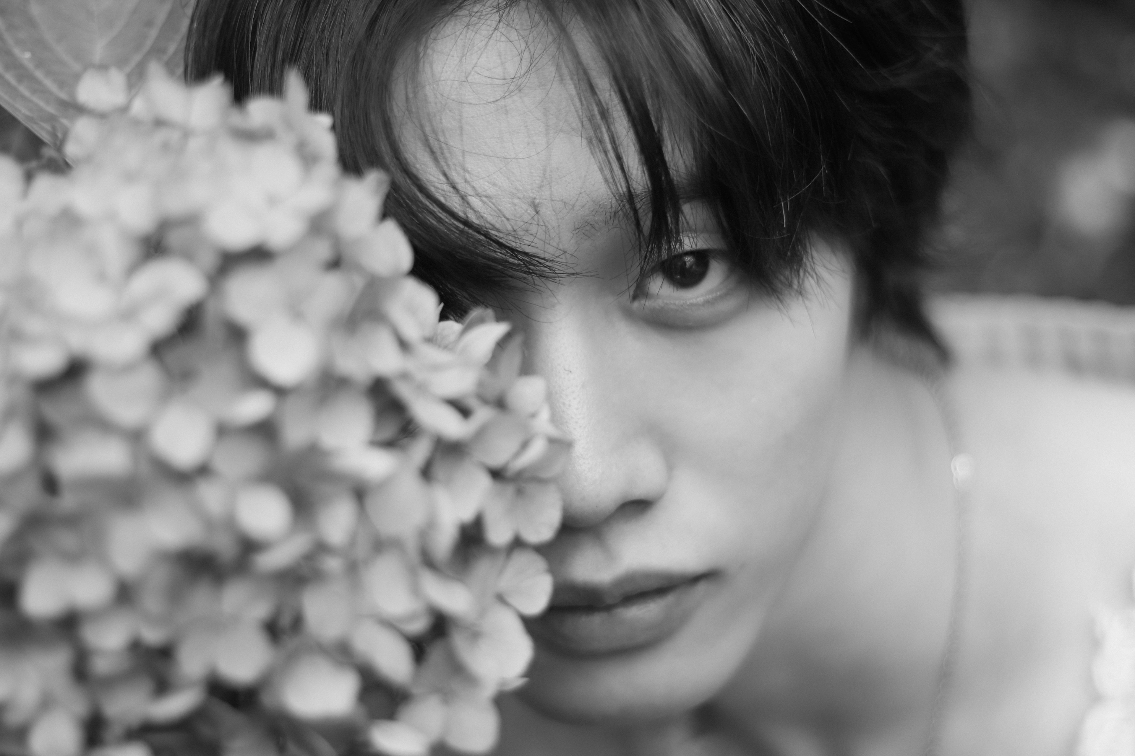 Retrato en blanco y negro de una persona joven con una flor cerca de su cara