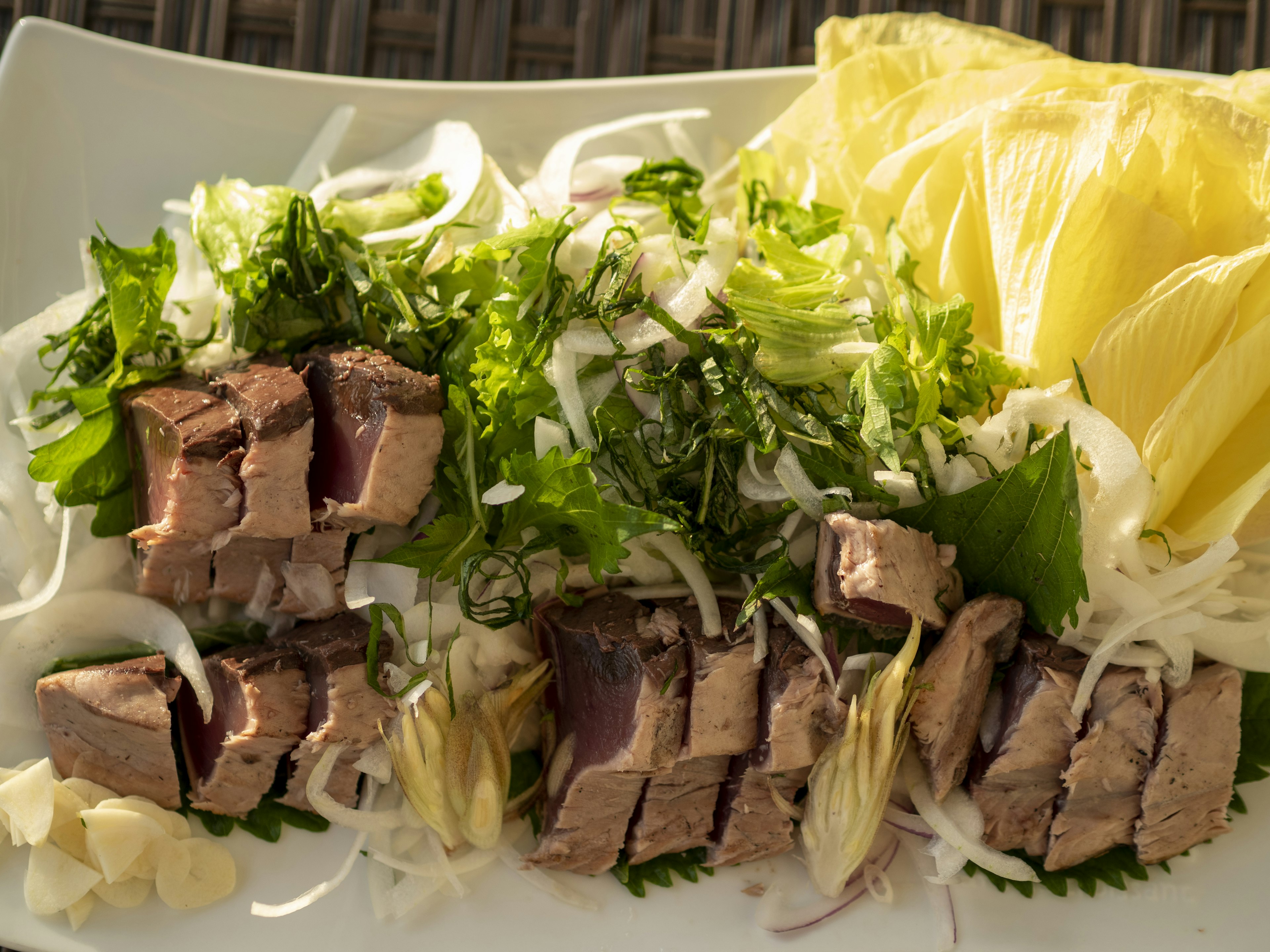 新鮮なハーブと野菜の上に盛り付けられた肉のスライス