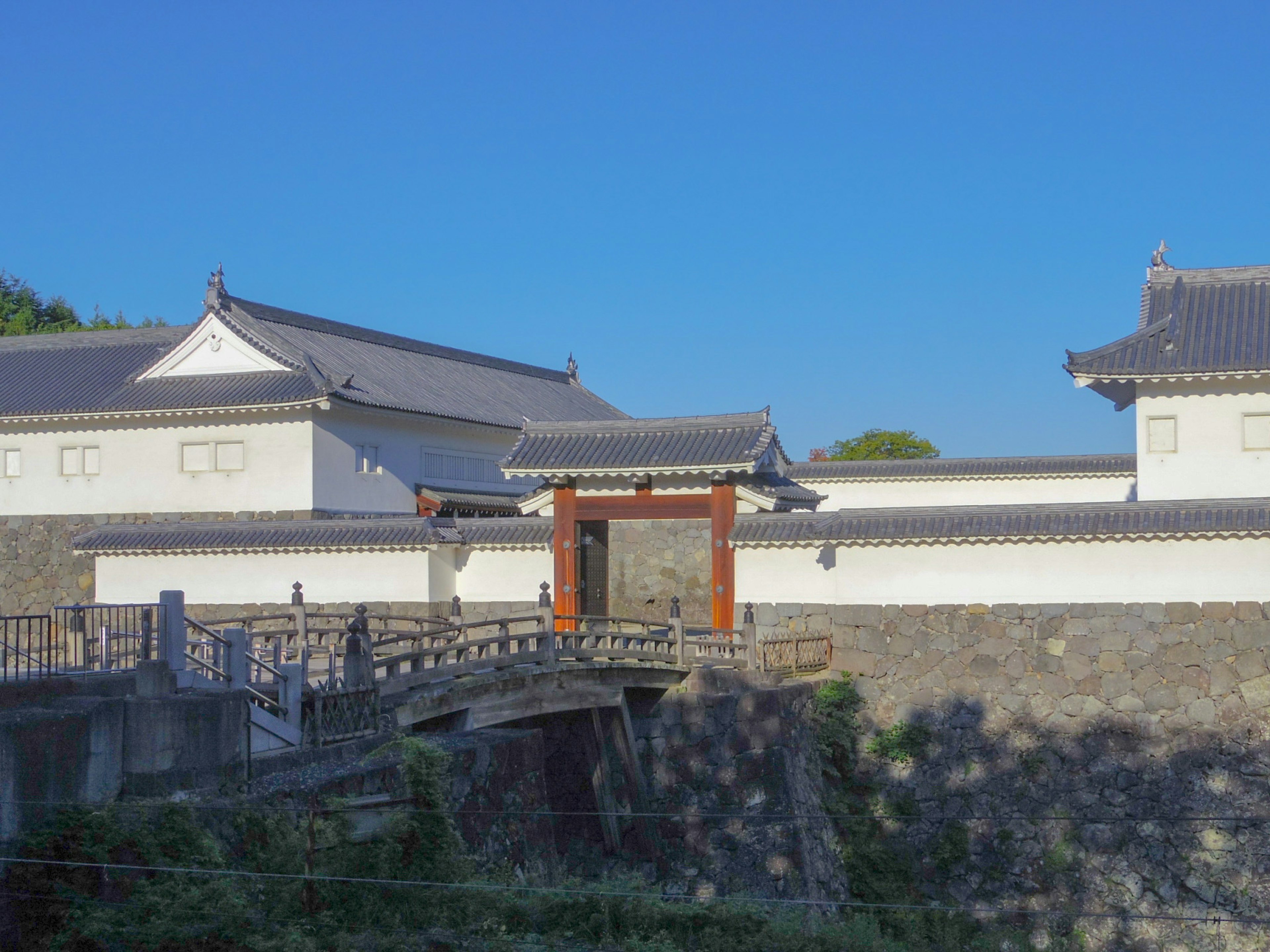 城堡建築的景觀，白色牆壁和傳統屋頂旁邊有一座橋