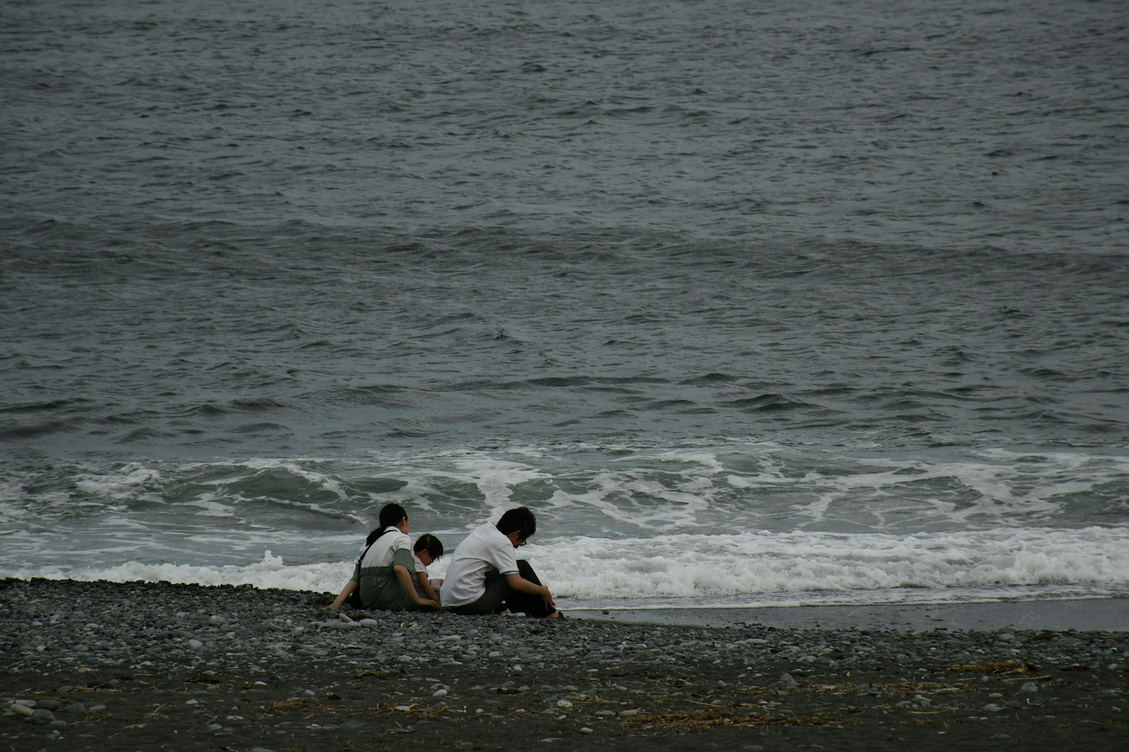 สองคนที่นั่งอยู่บนชายหาดกับคลื่นอ่อน