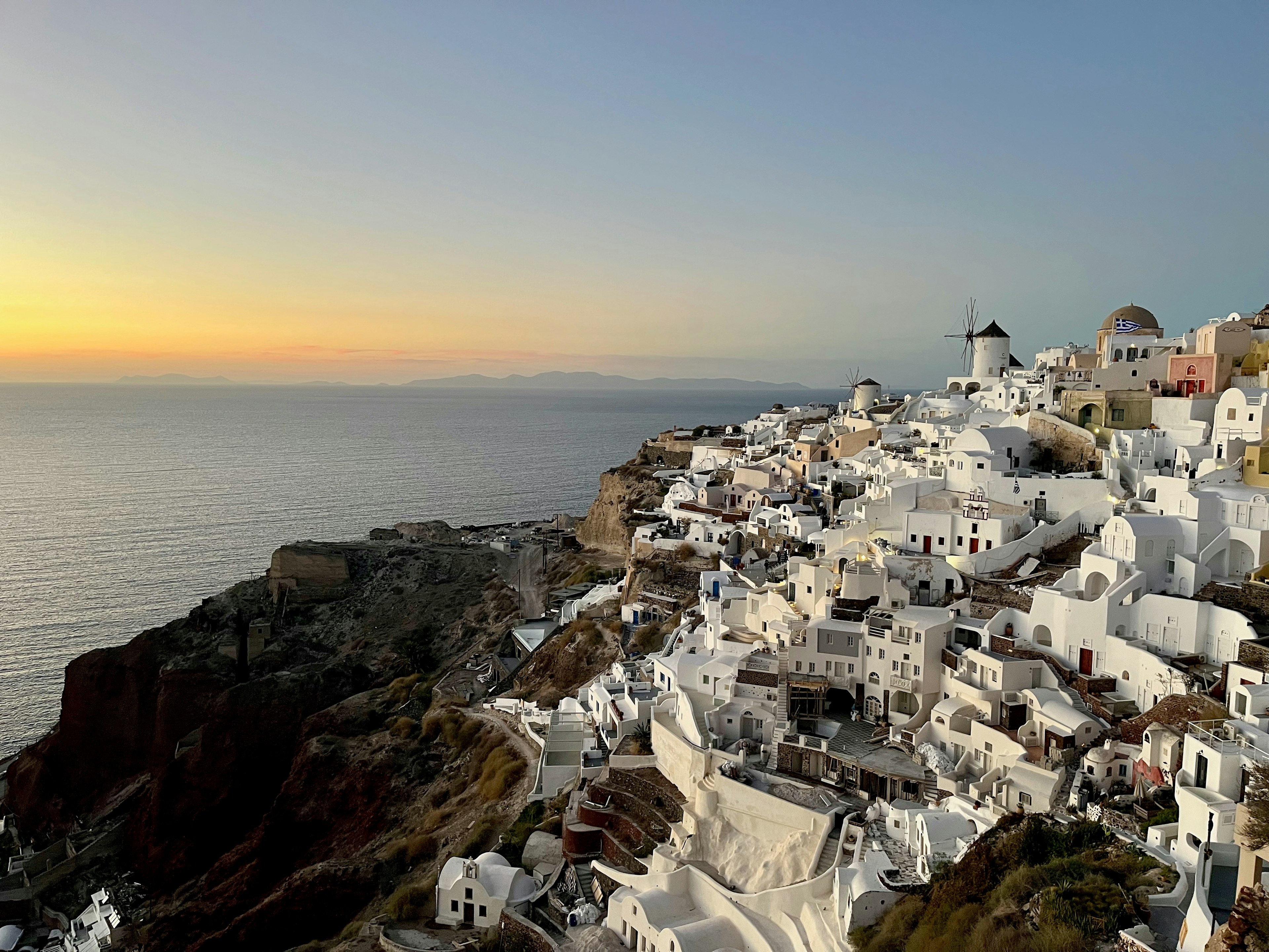 Edifici bianchi dell'isola di Santorini che affacciano sul mare Egeo al tramonto