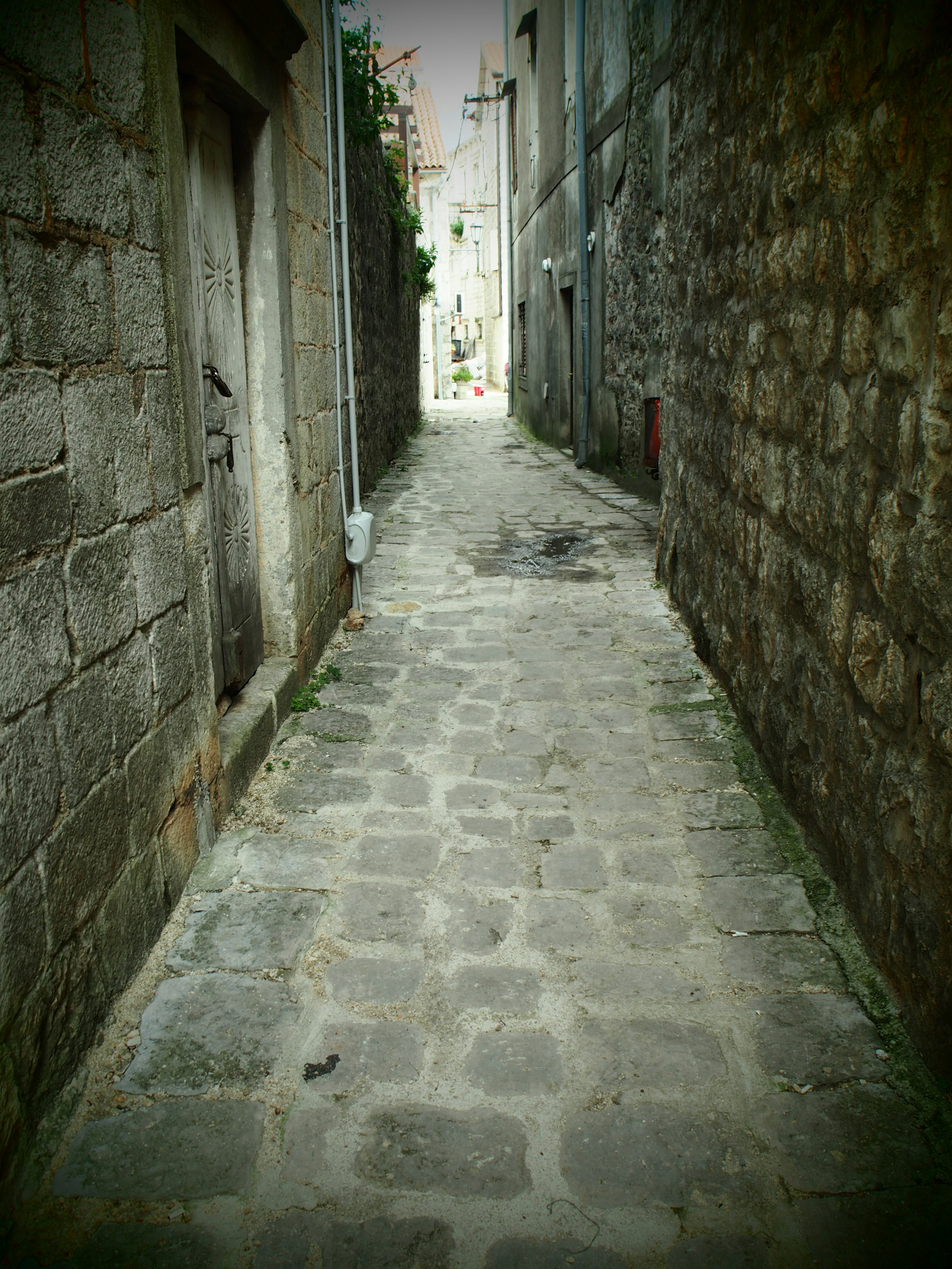 Callejón estrecho de adoquines con muros de piedra antiguos