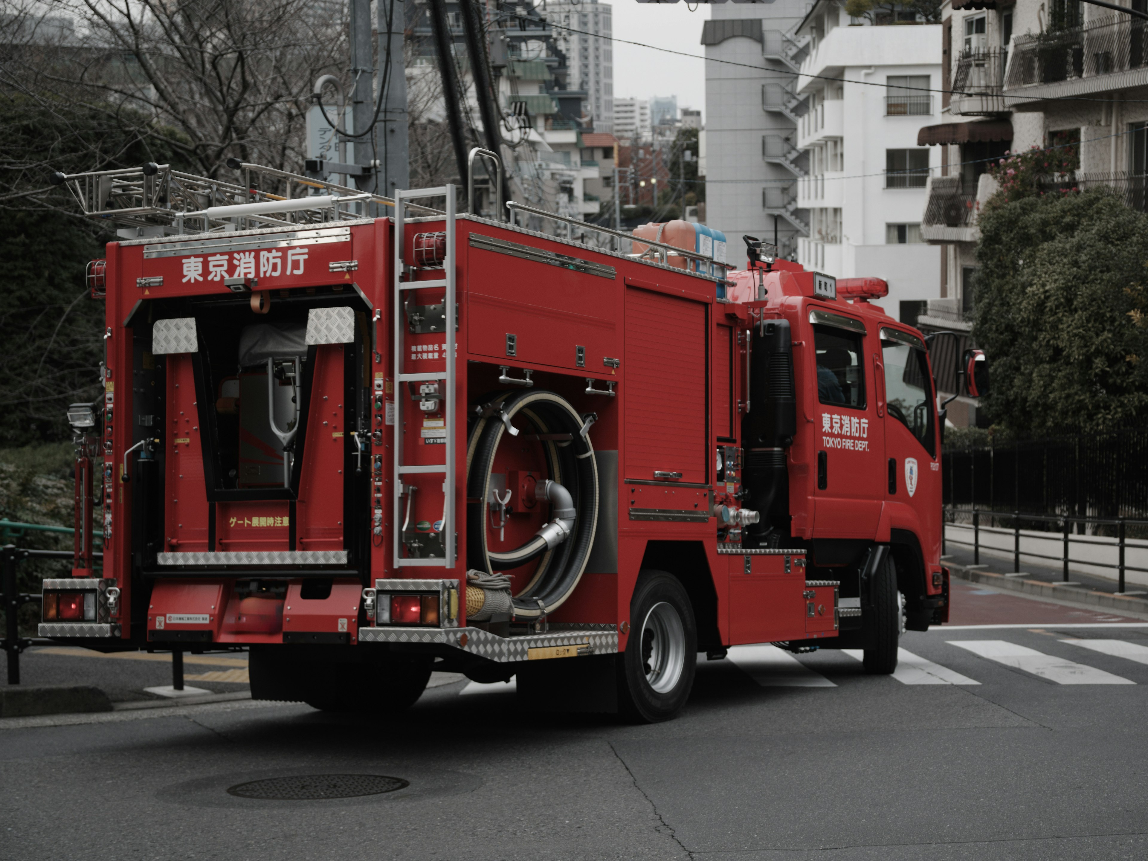 Un camión de bomberos rojo girando en una intersección urbana