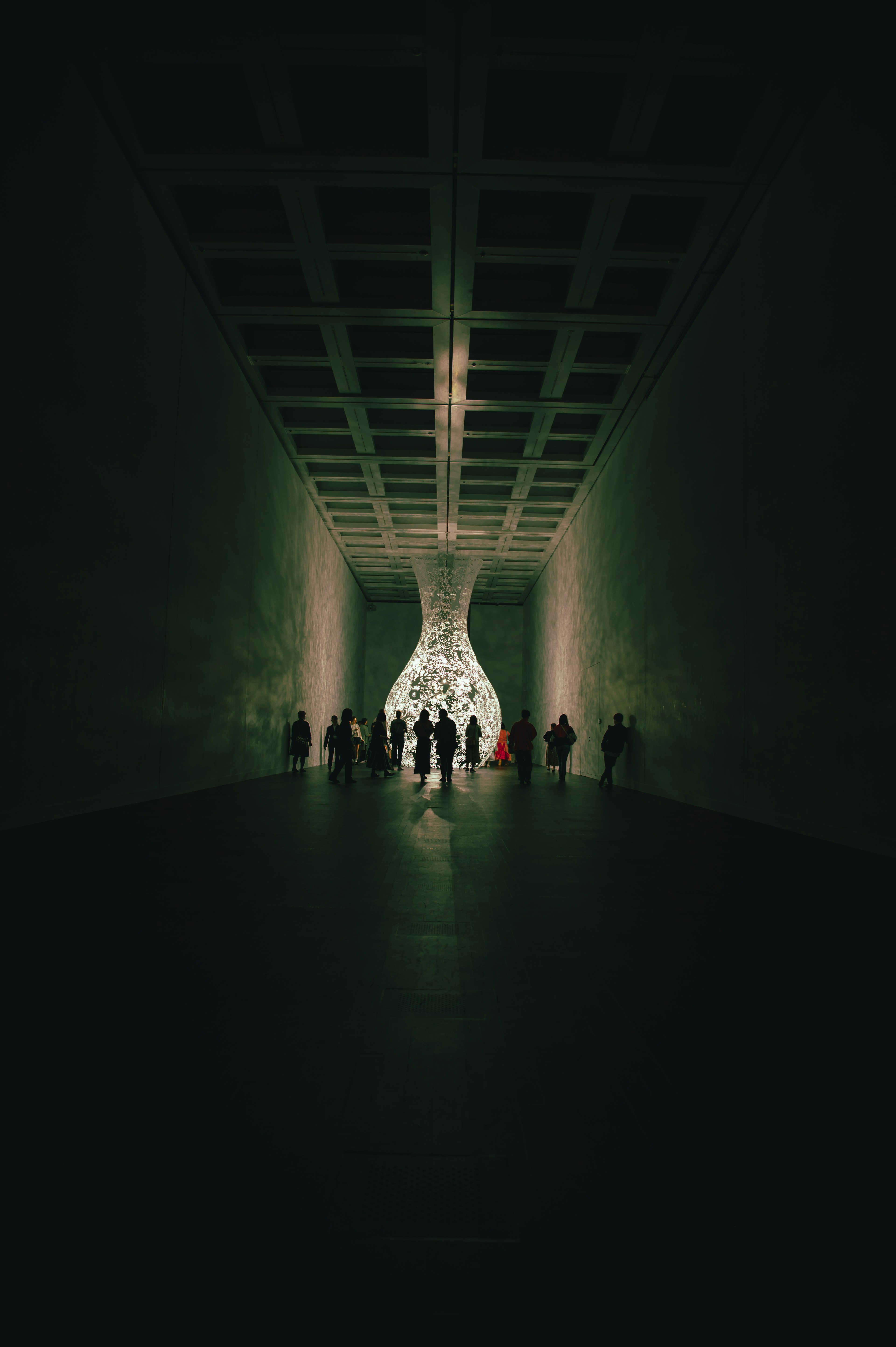 Persone in controluce in un tunnel scuro con un oggetto luminoso sullo sfondo