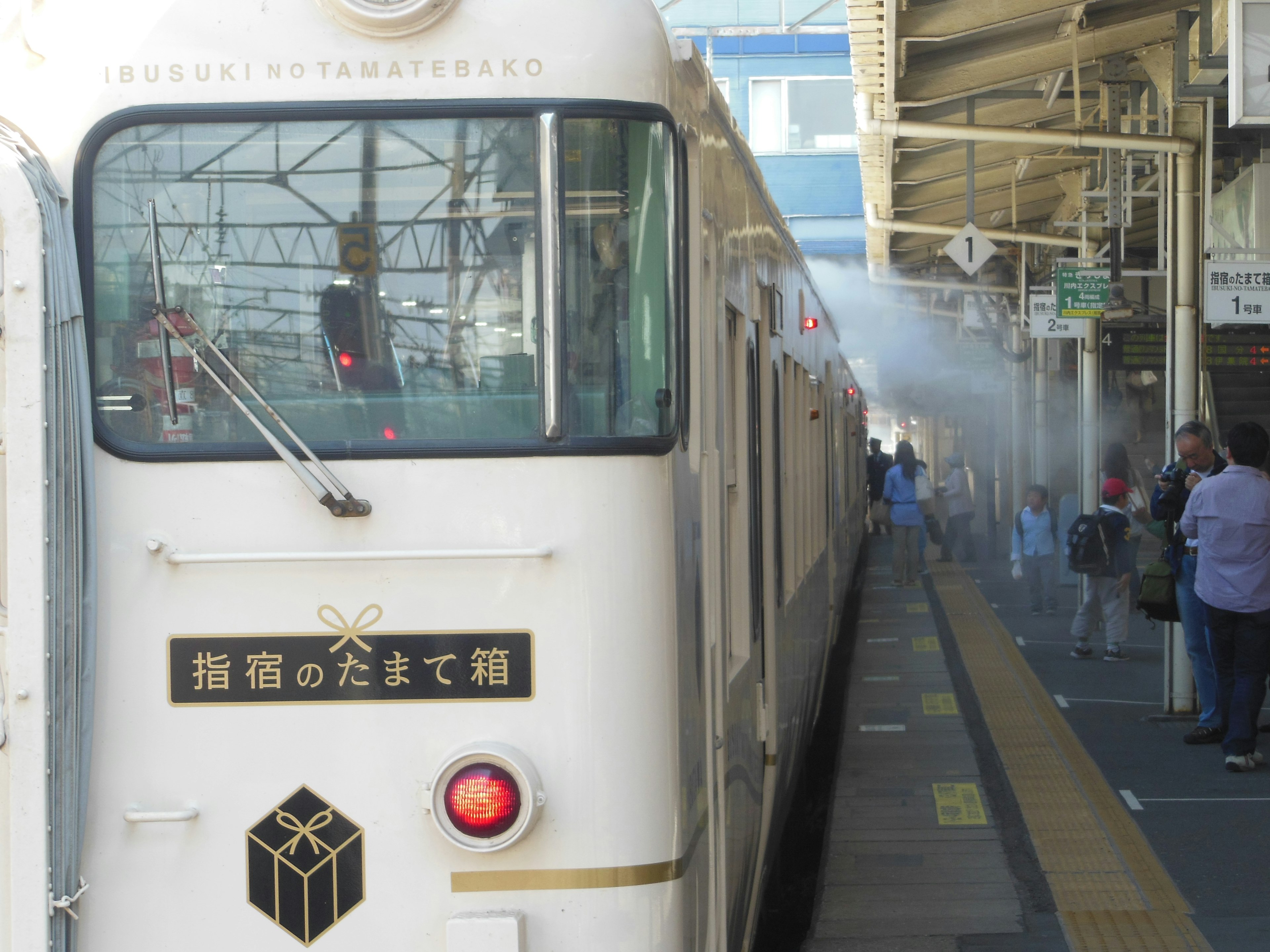 白い列車が駅に停車している 乗客がホームにいる