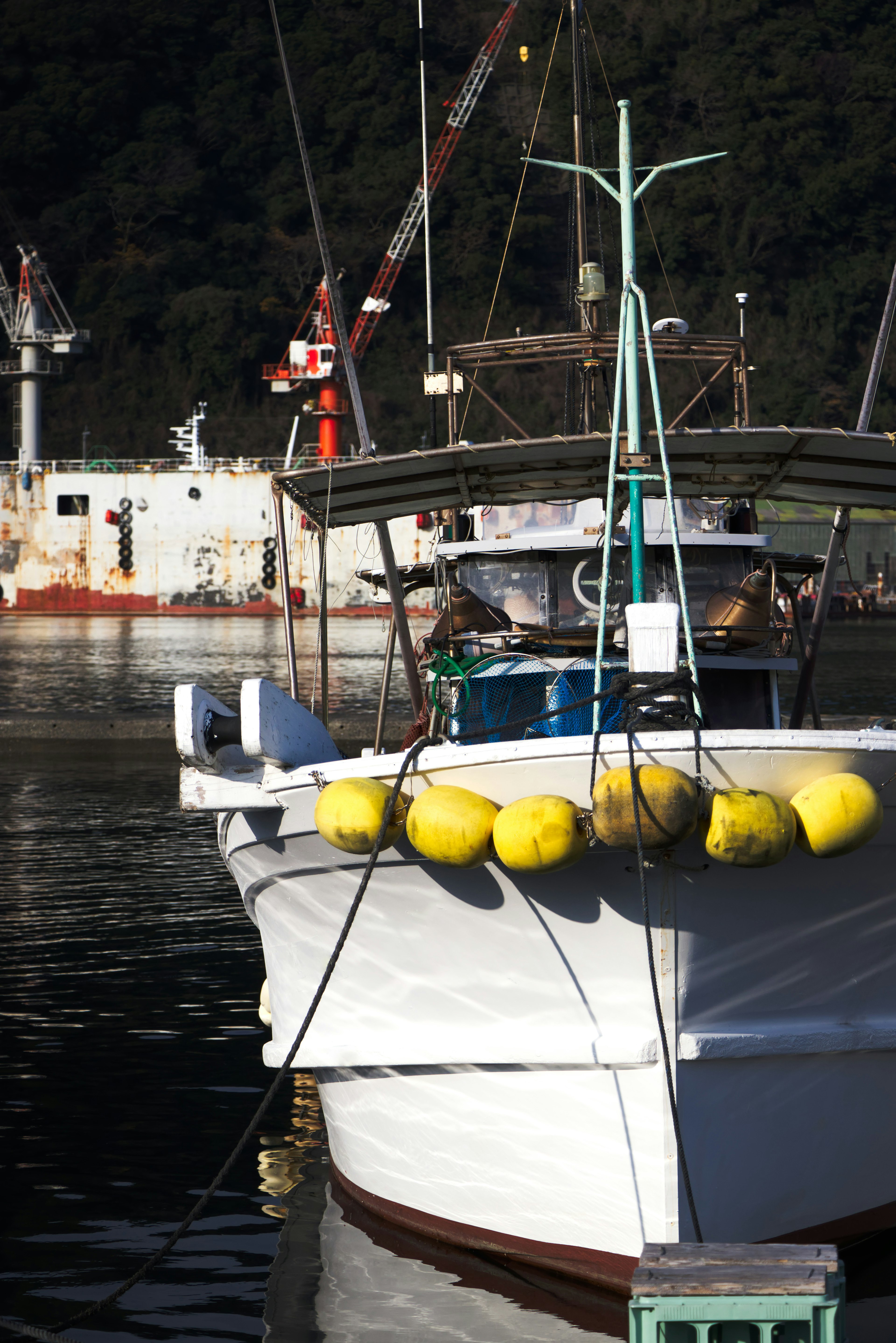 White fishing boat with yellow buoys in a harbor