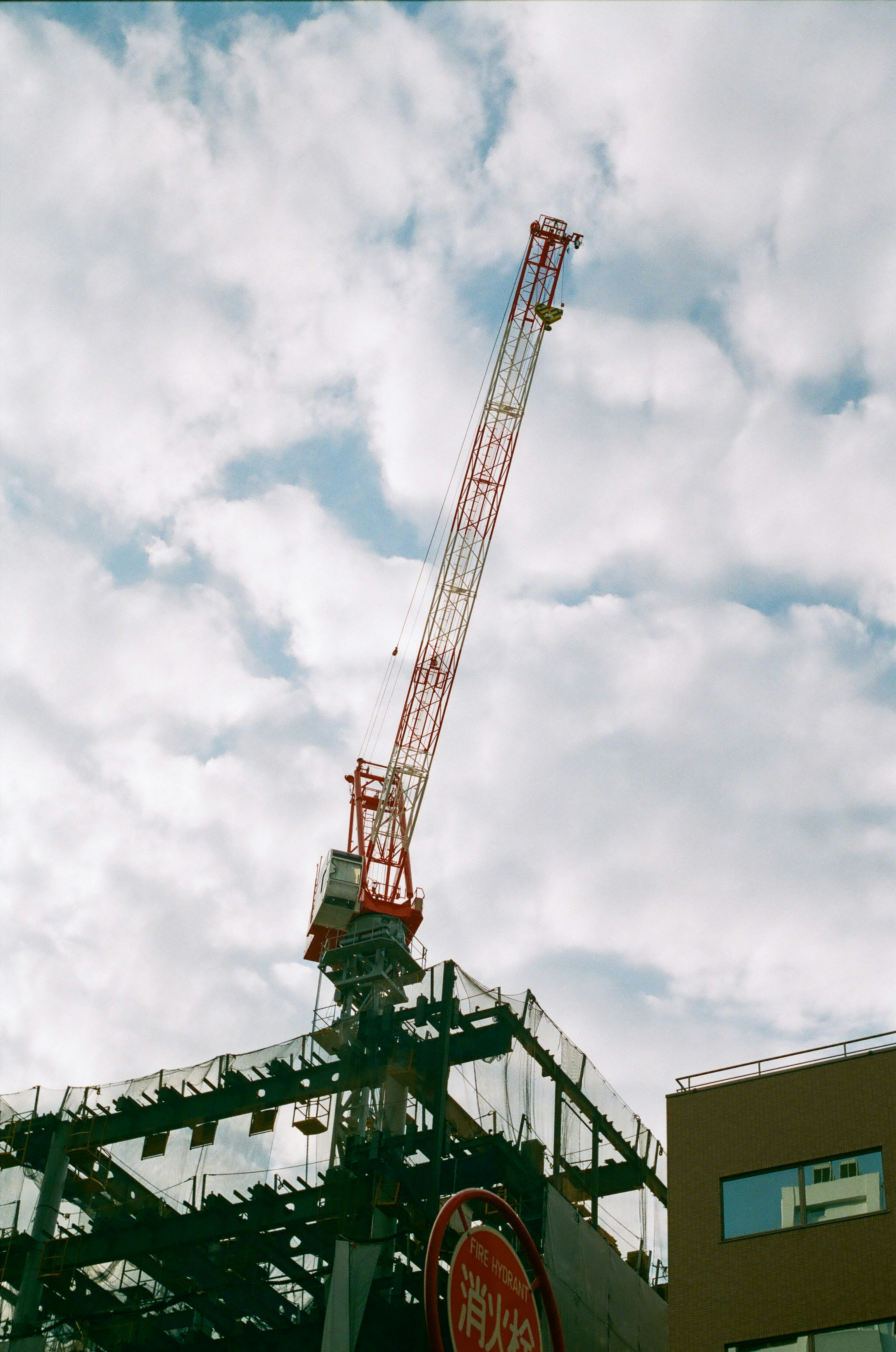 Construction crane towering against a backdrop of blue sky and white clouds