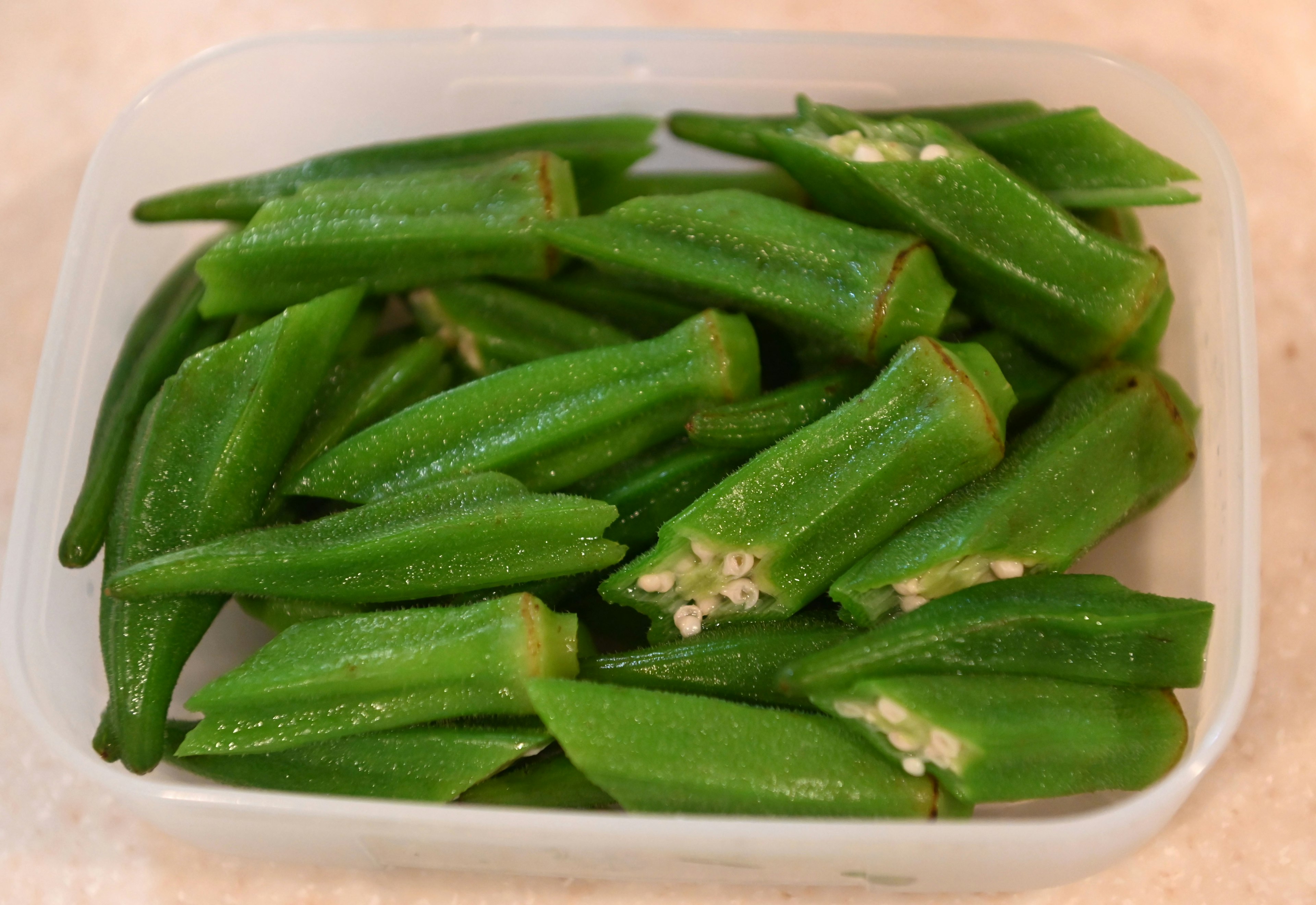 Frische grüne Okra in einem klaren Behälter