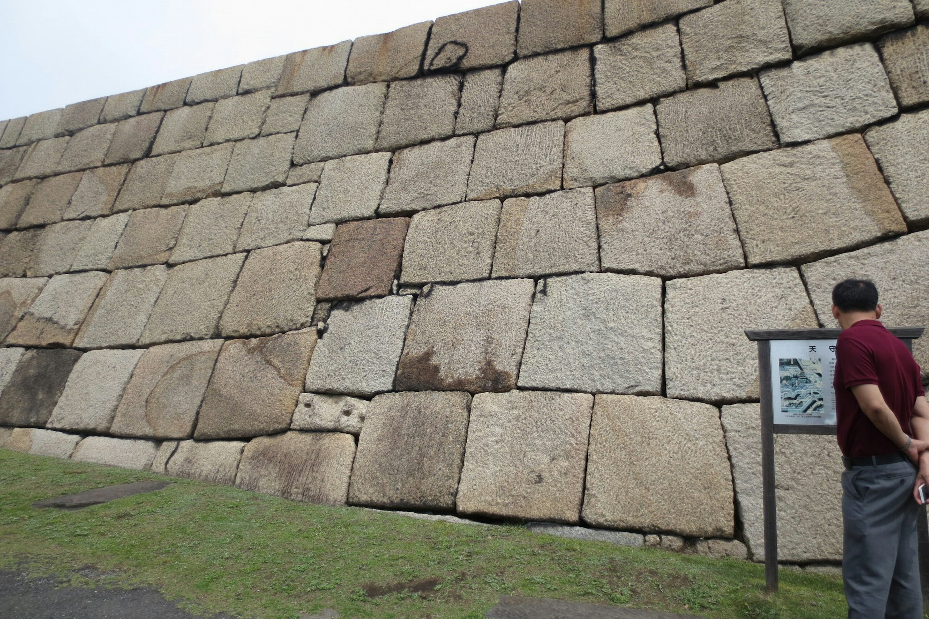 Un grande muro di pietra inclinato composto da massi con una persona che osserva