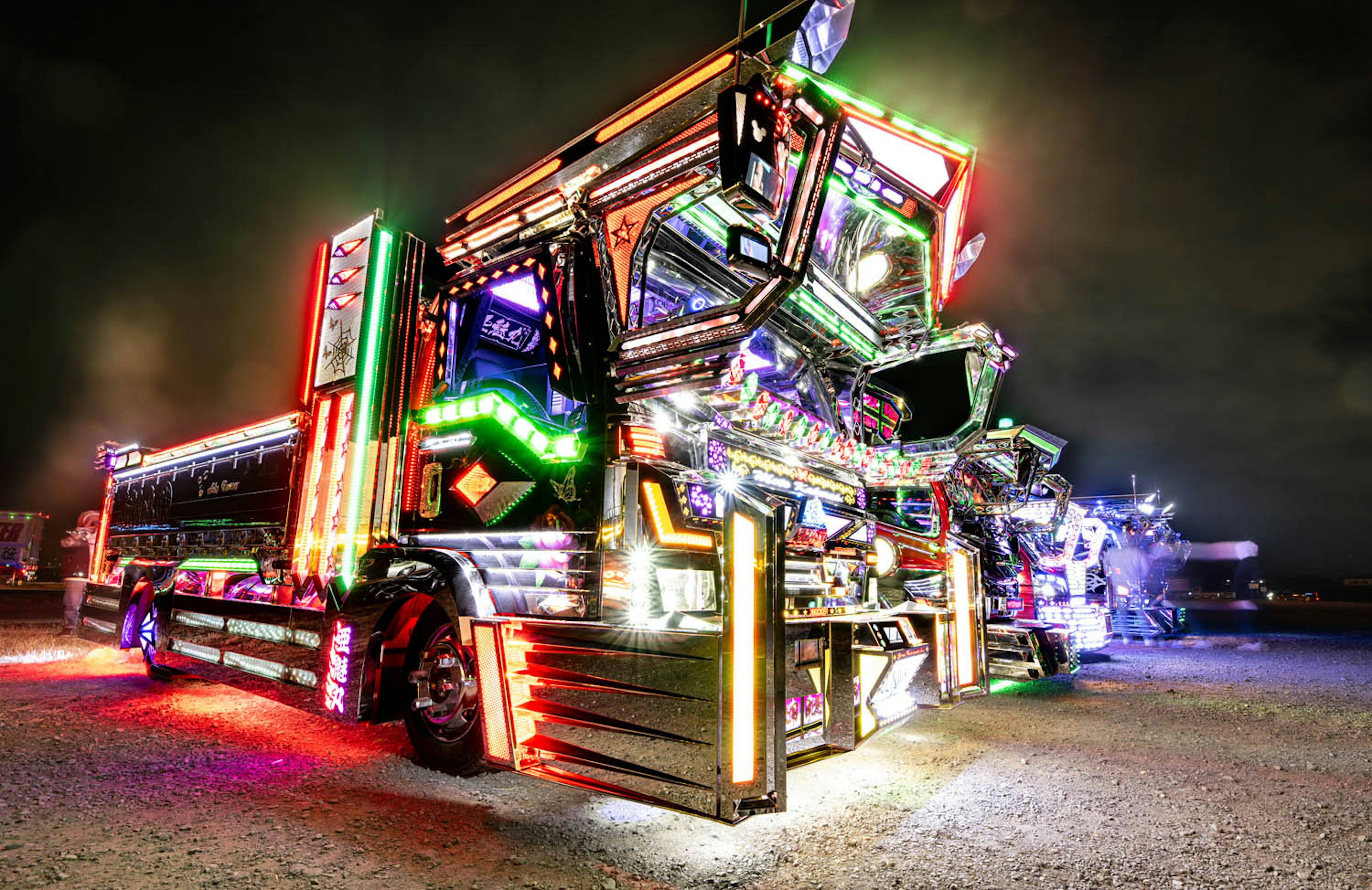 A brightly lit truck with colorful decorations stands out against a night backdrop