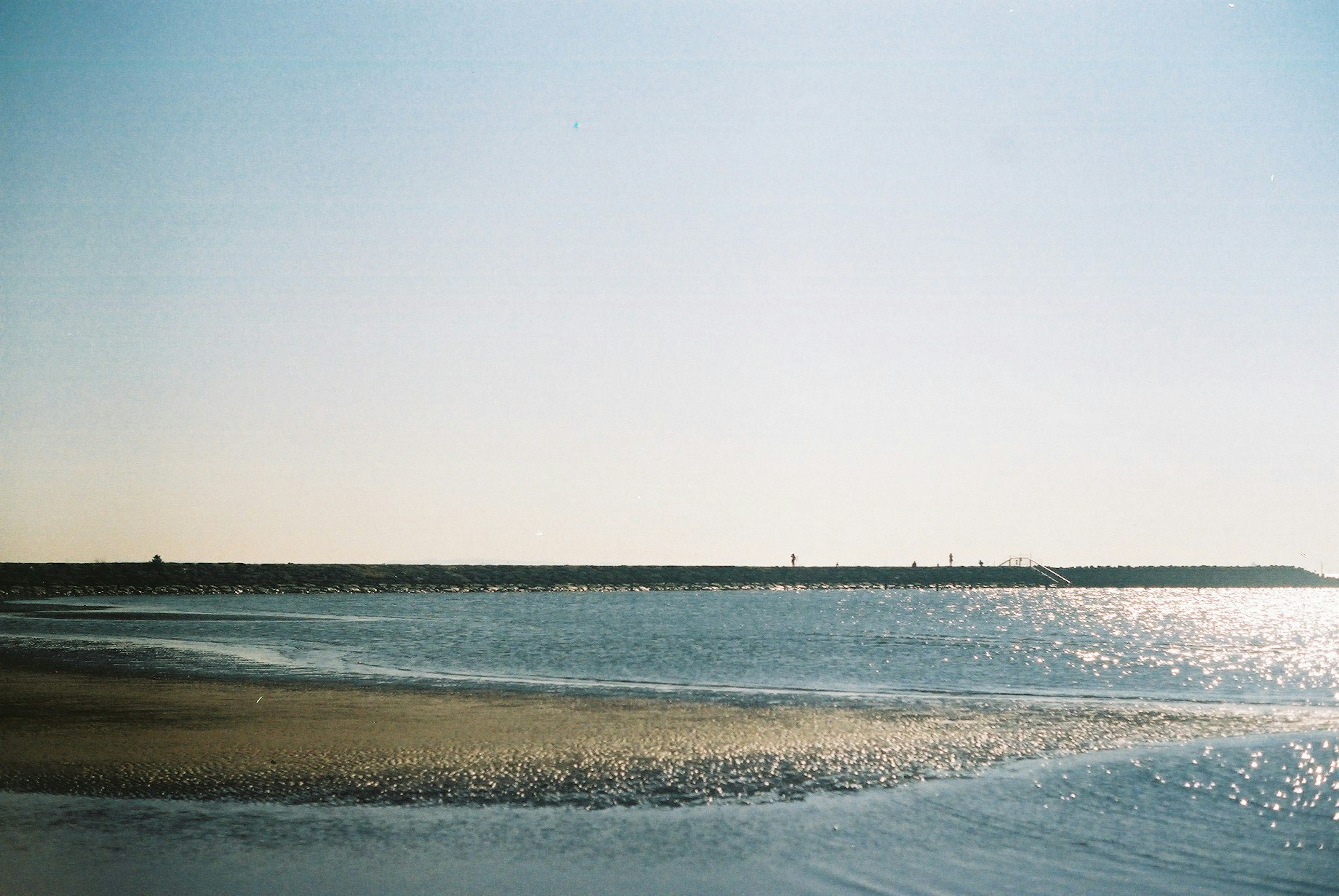 Scène de mer calme et ciel bleu avec un brise-lames au loin