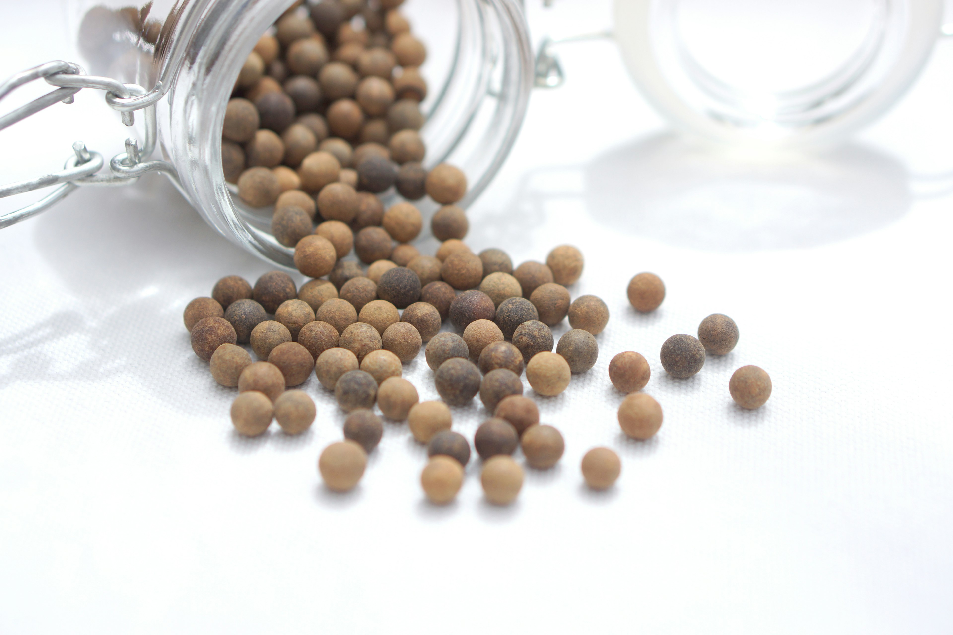 Brown spice balls spilled from a glass jar