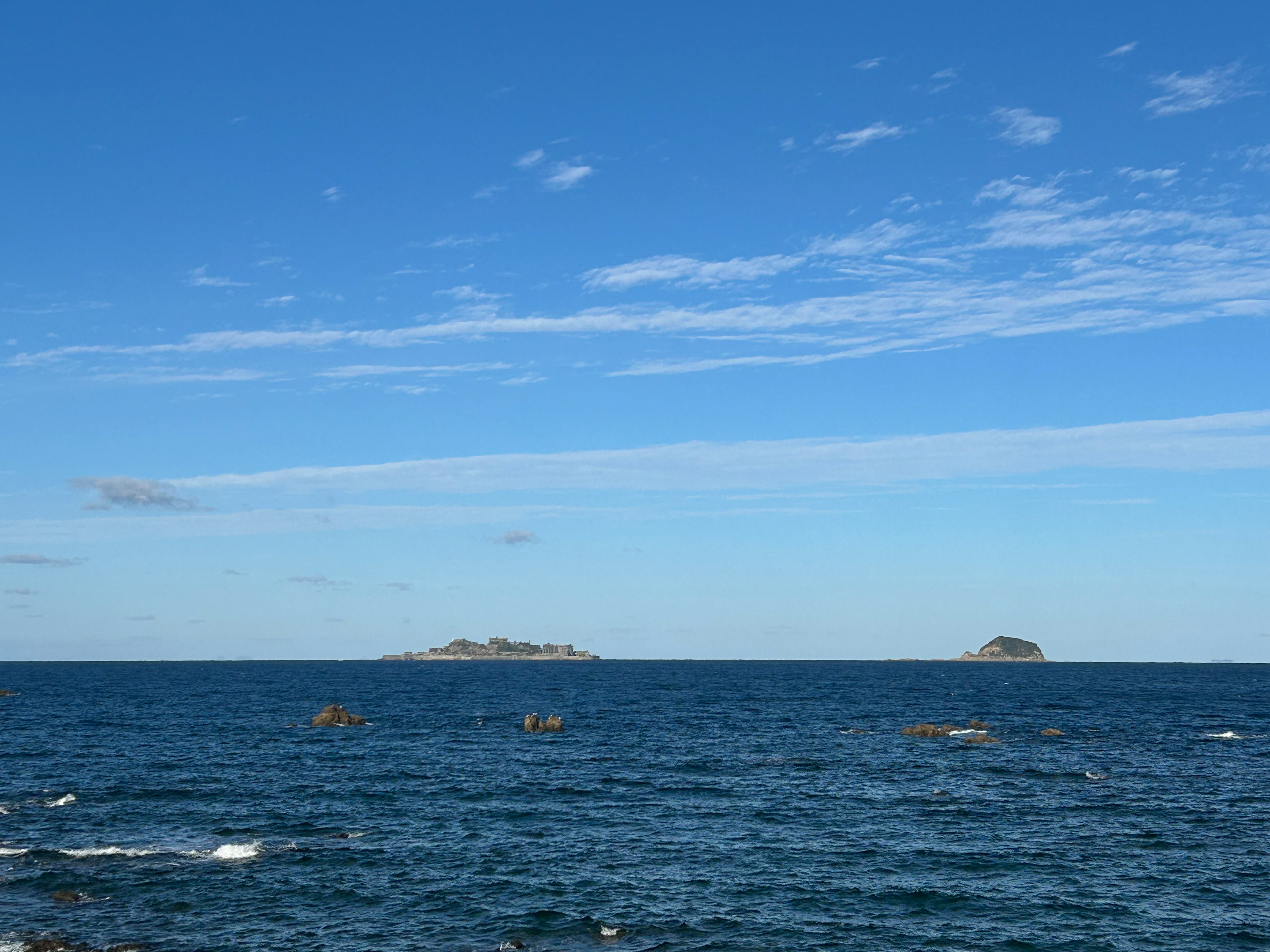 藍色海洋的風景，地平線上有兩個小島，天空晴朗