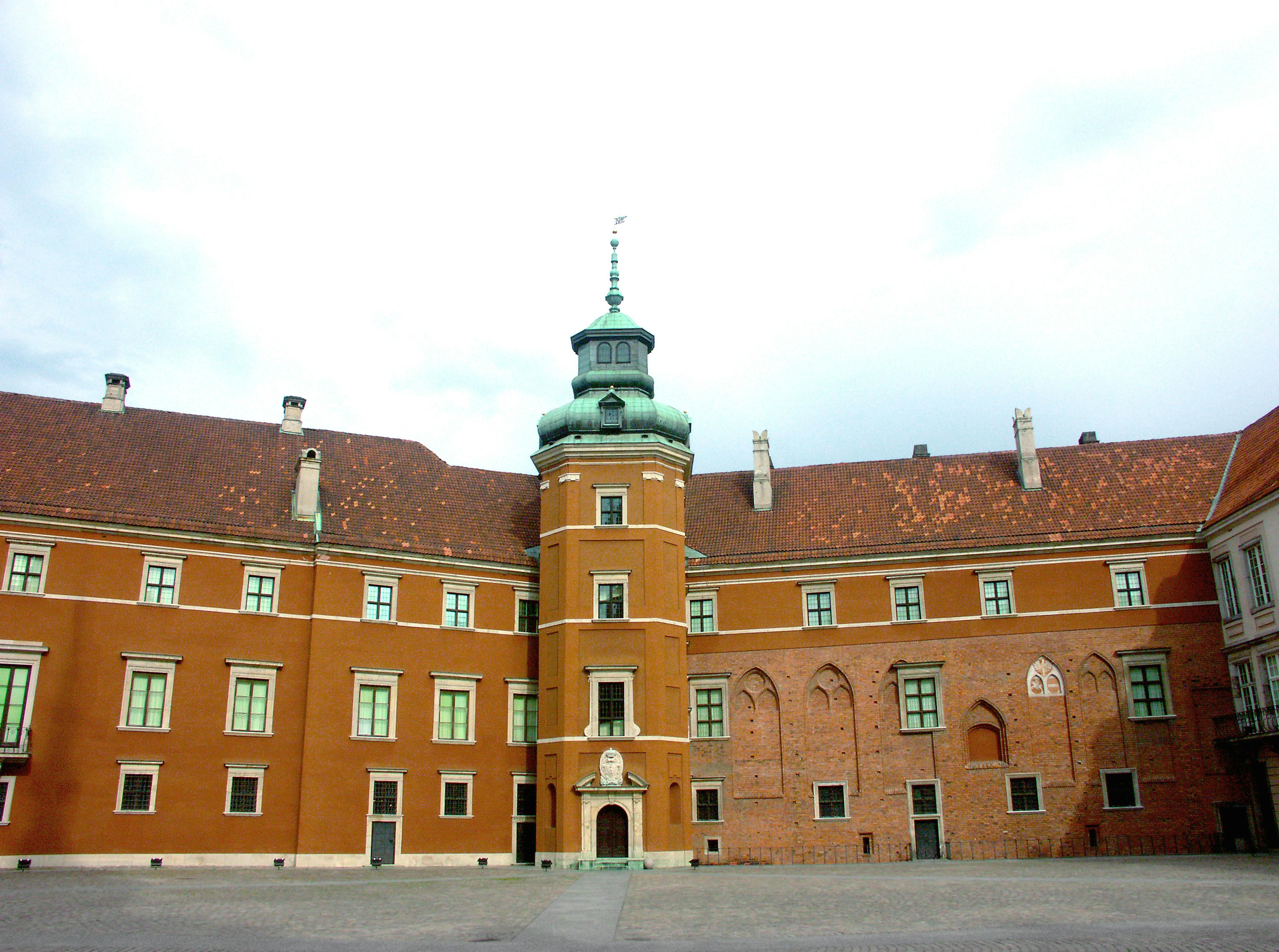 Exterior de un castillo histórico en Varsovia Polonia con una cúpula verde y paredes de ladrillo rojo