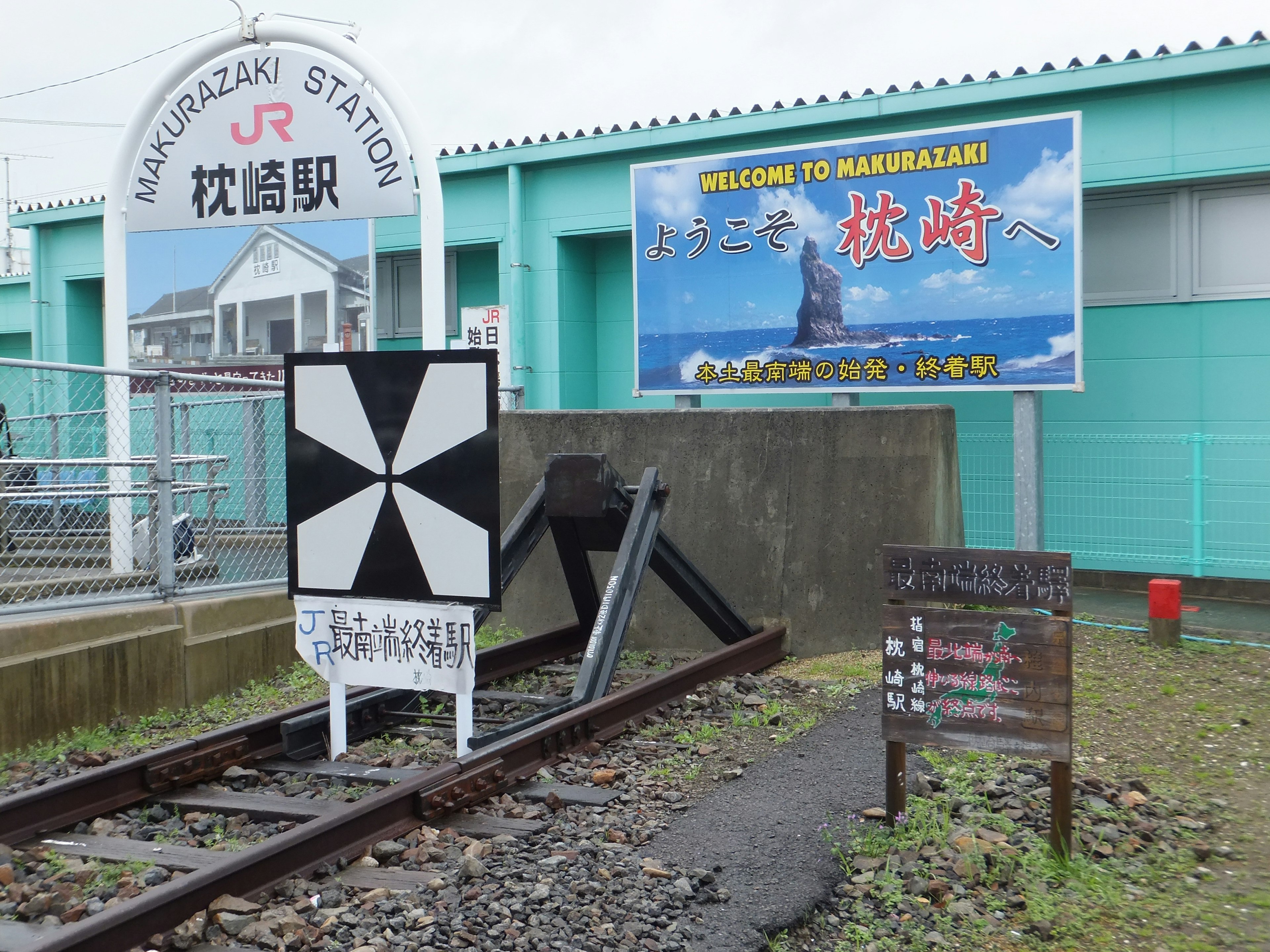 Vista del cartel de la estación de Hamazaki y las vías con un anuncio