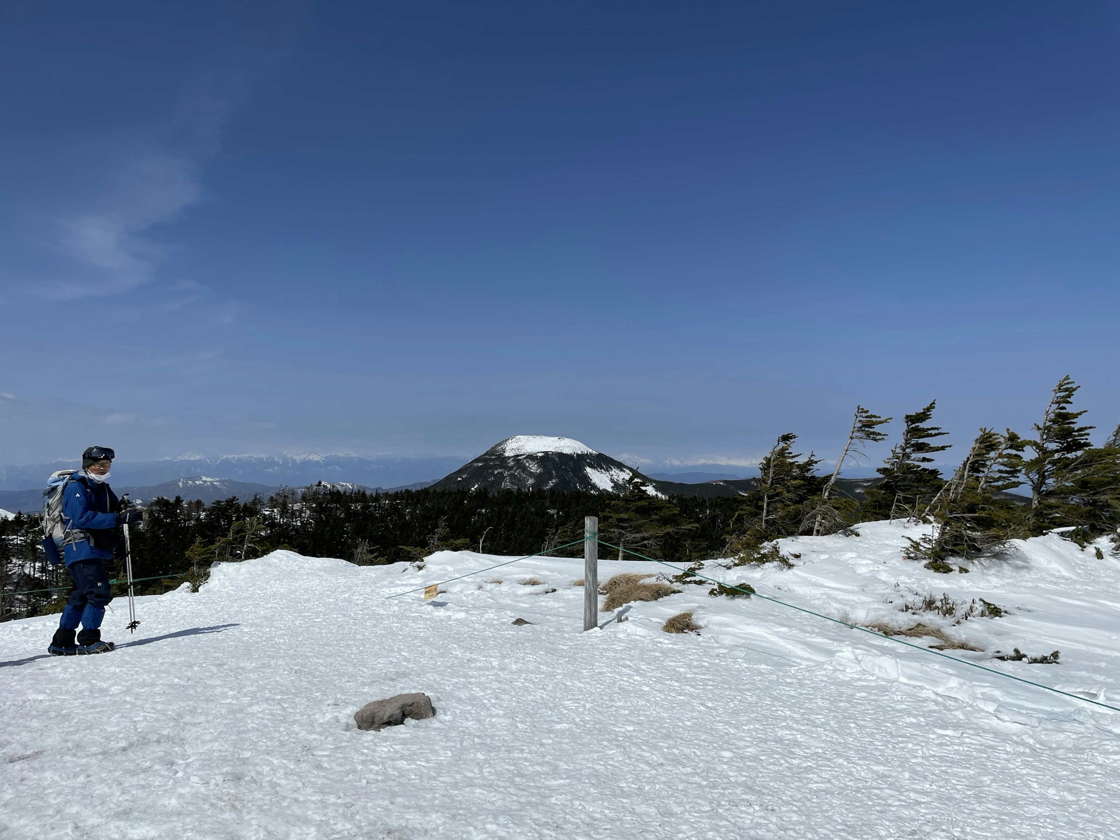 A person skiing on a snow-covered mountain with a clear blue sky