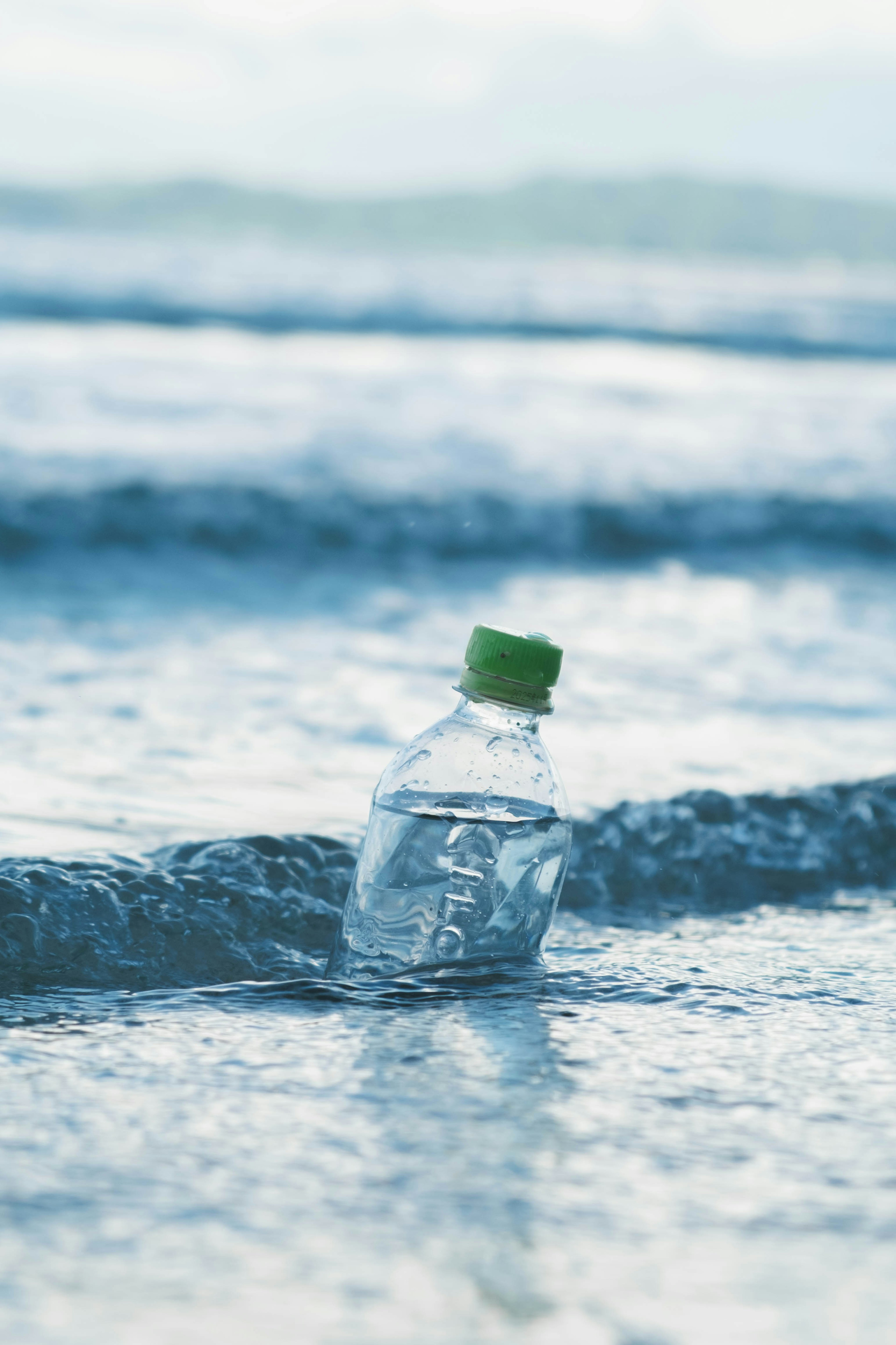 Botella de agua de plástico con tapa verde en la orilla