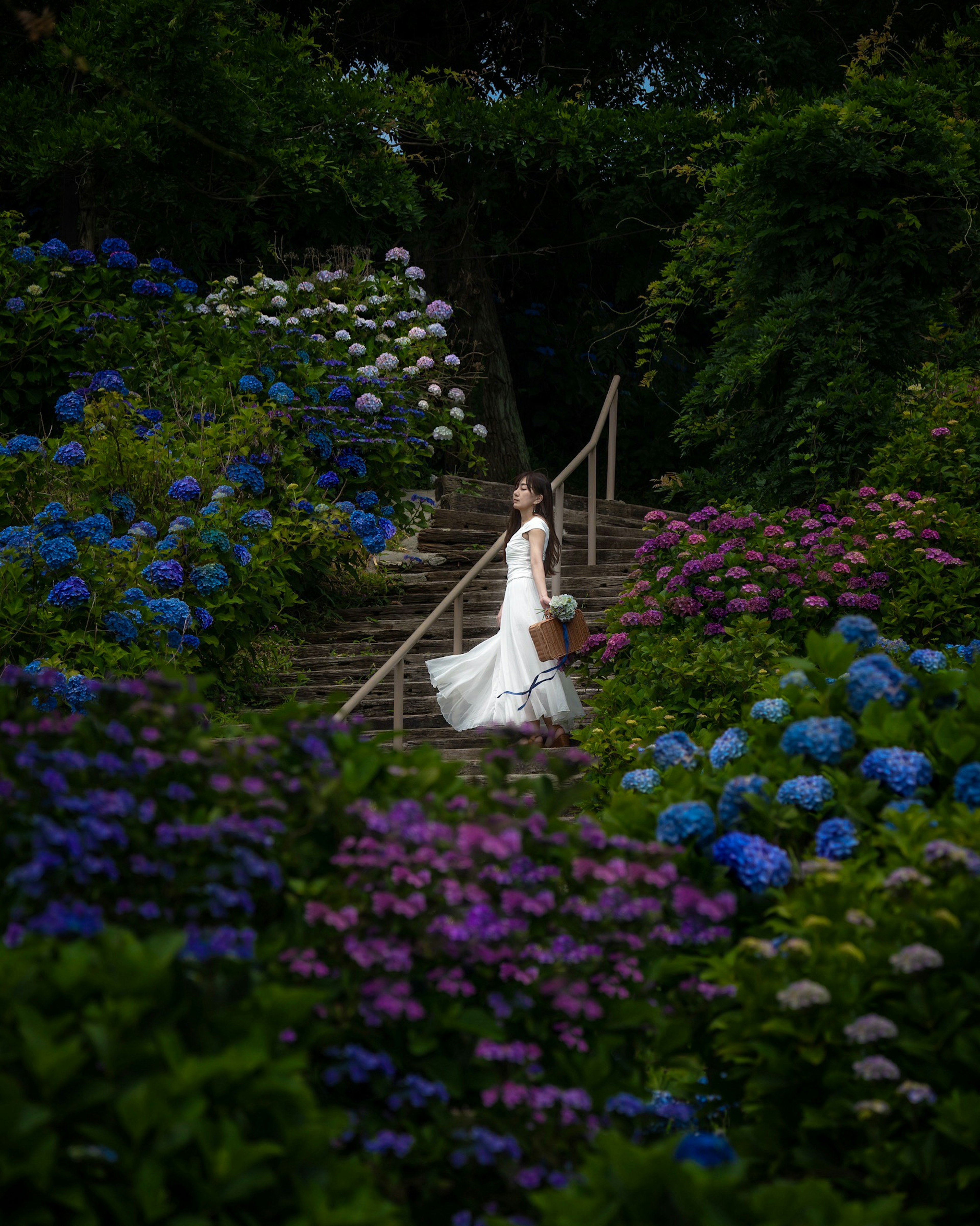 Une femme en robe blanche montant des escaliers entourée de fleurs colorées