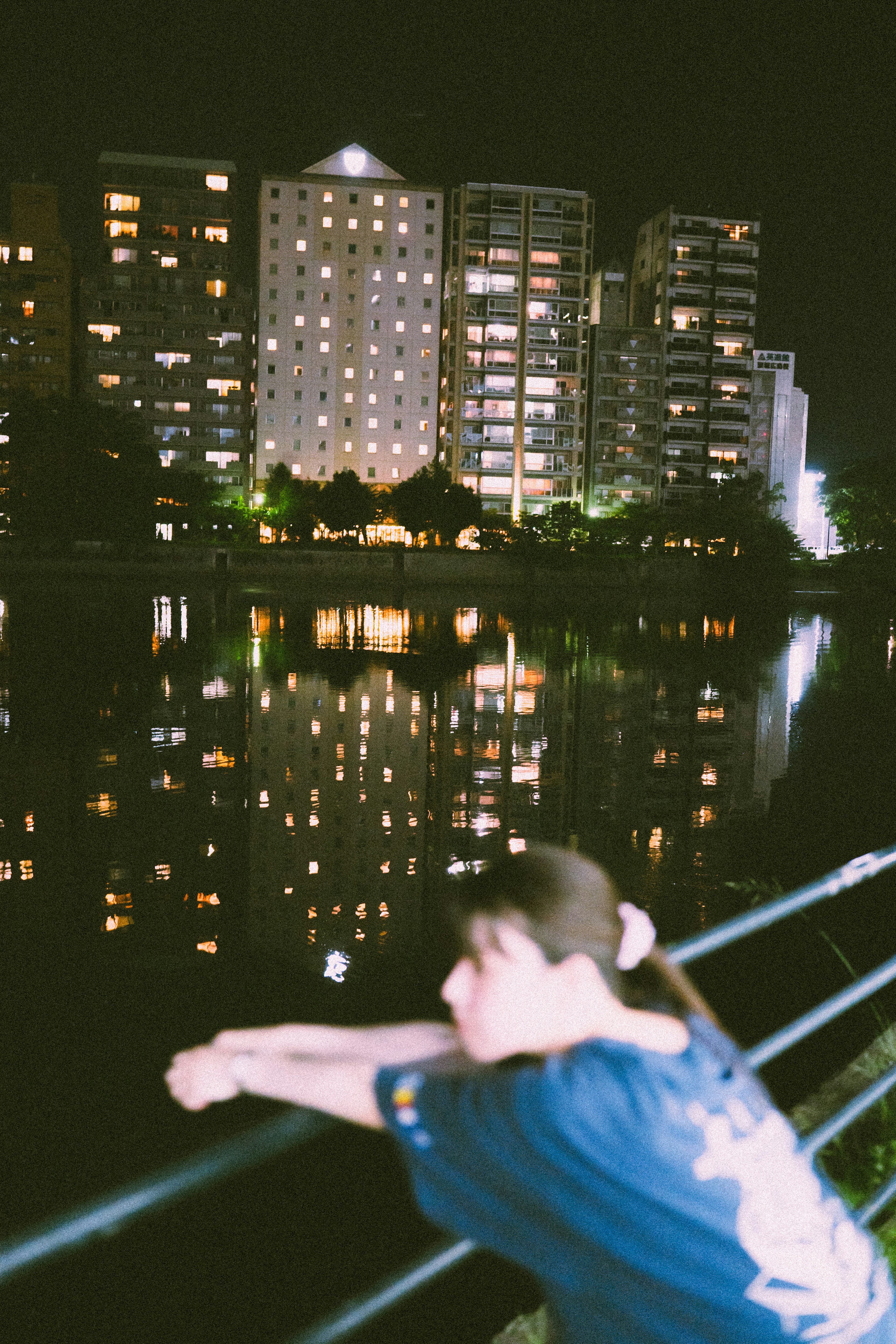 Persona relajándose junto al río por la noche con el horizonte de la ciudad