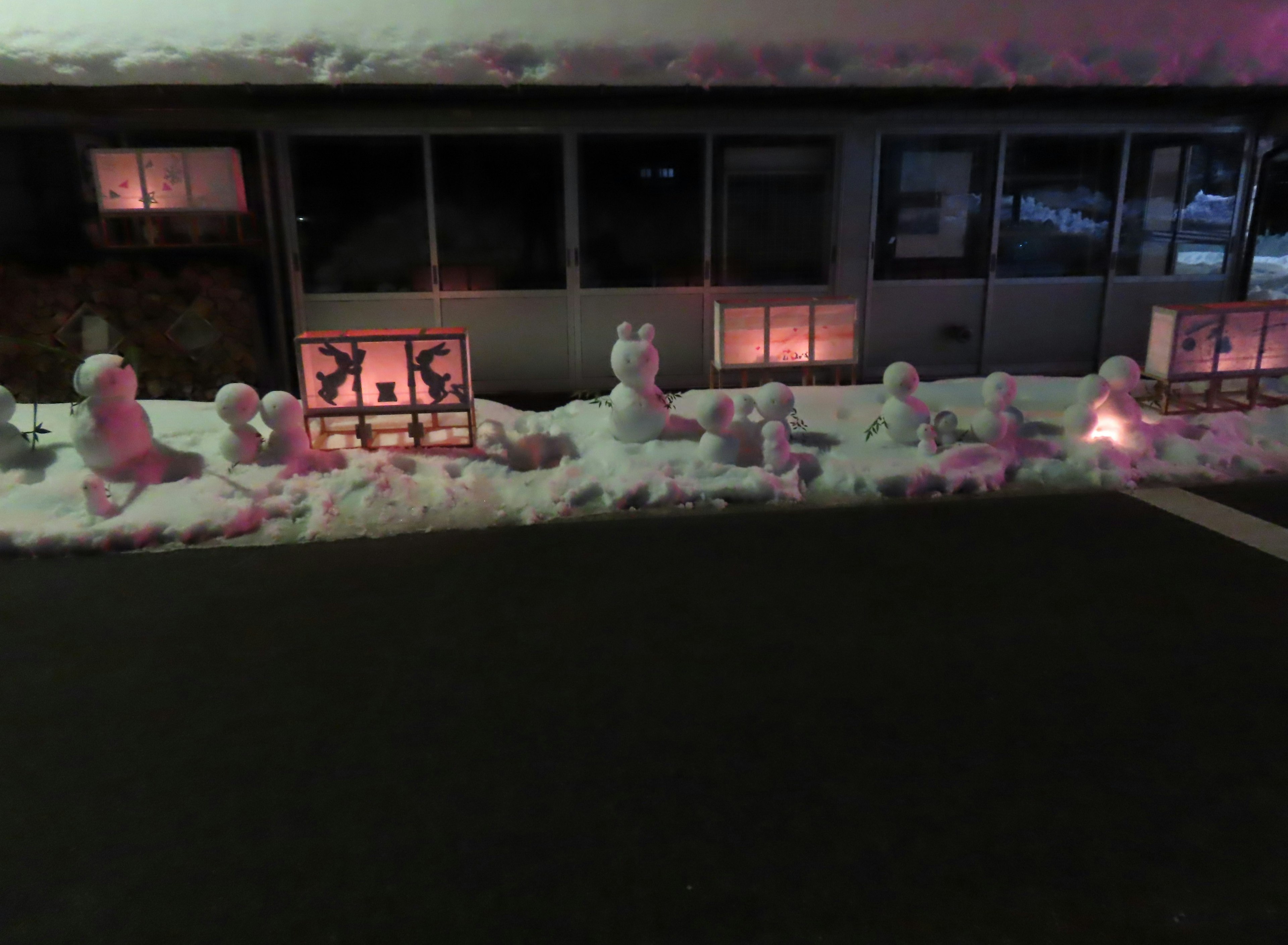 Escena nocturna con esculturas de nieve alineadas luz cálida de las ventanas