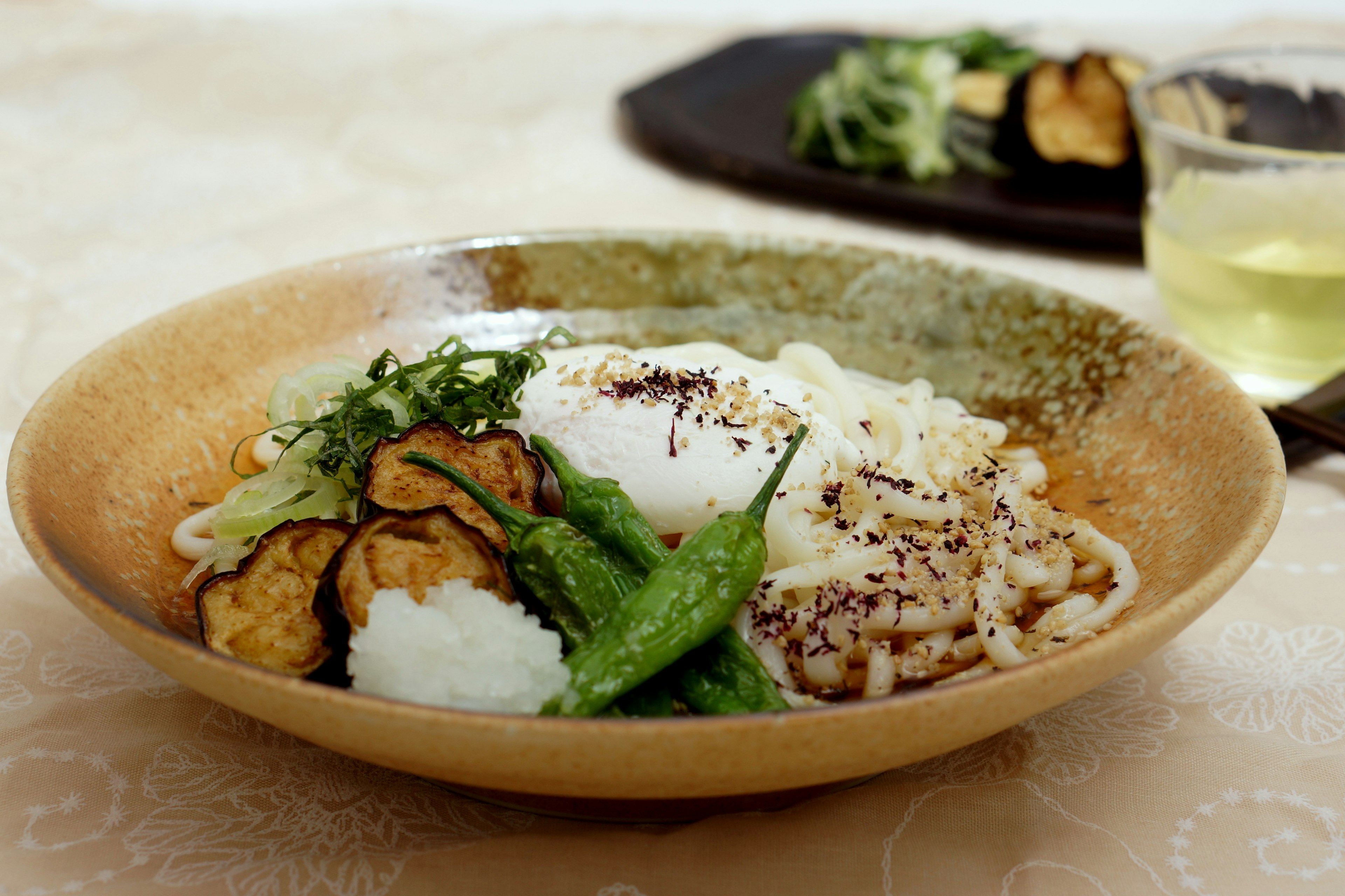 Tazón de udon japonés bellamente presentado con huevo poché y aderezos de verduras