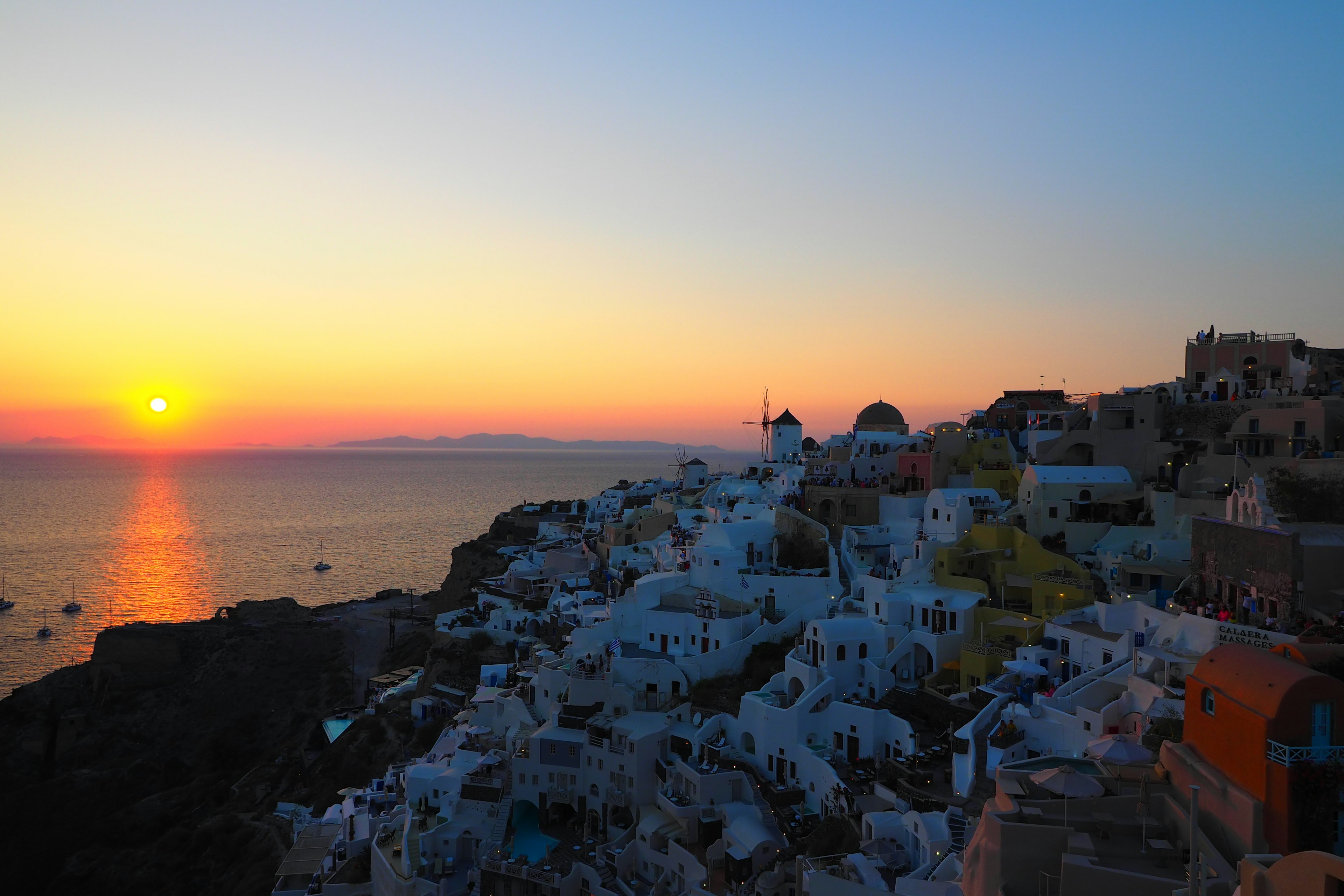 Matahari terbenam di Santorini dengan bangunan putih dan pemandangan laut