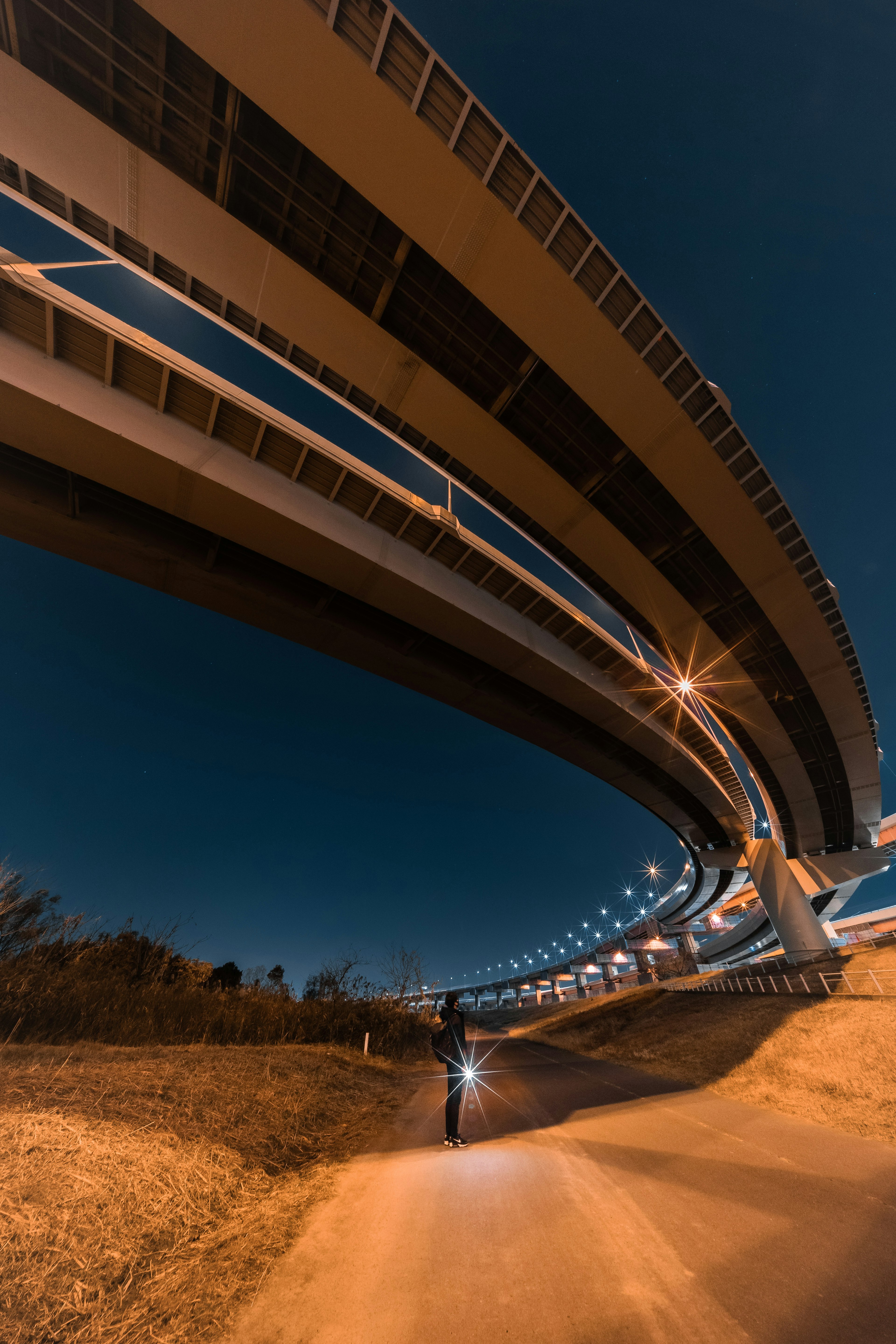 夜晚從下方觀察到的拱形高速公路結構和騎自行車的人