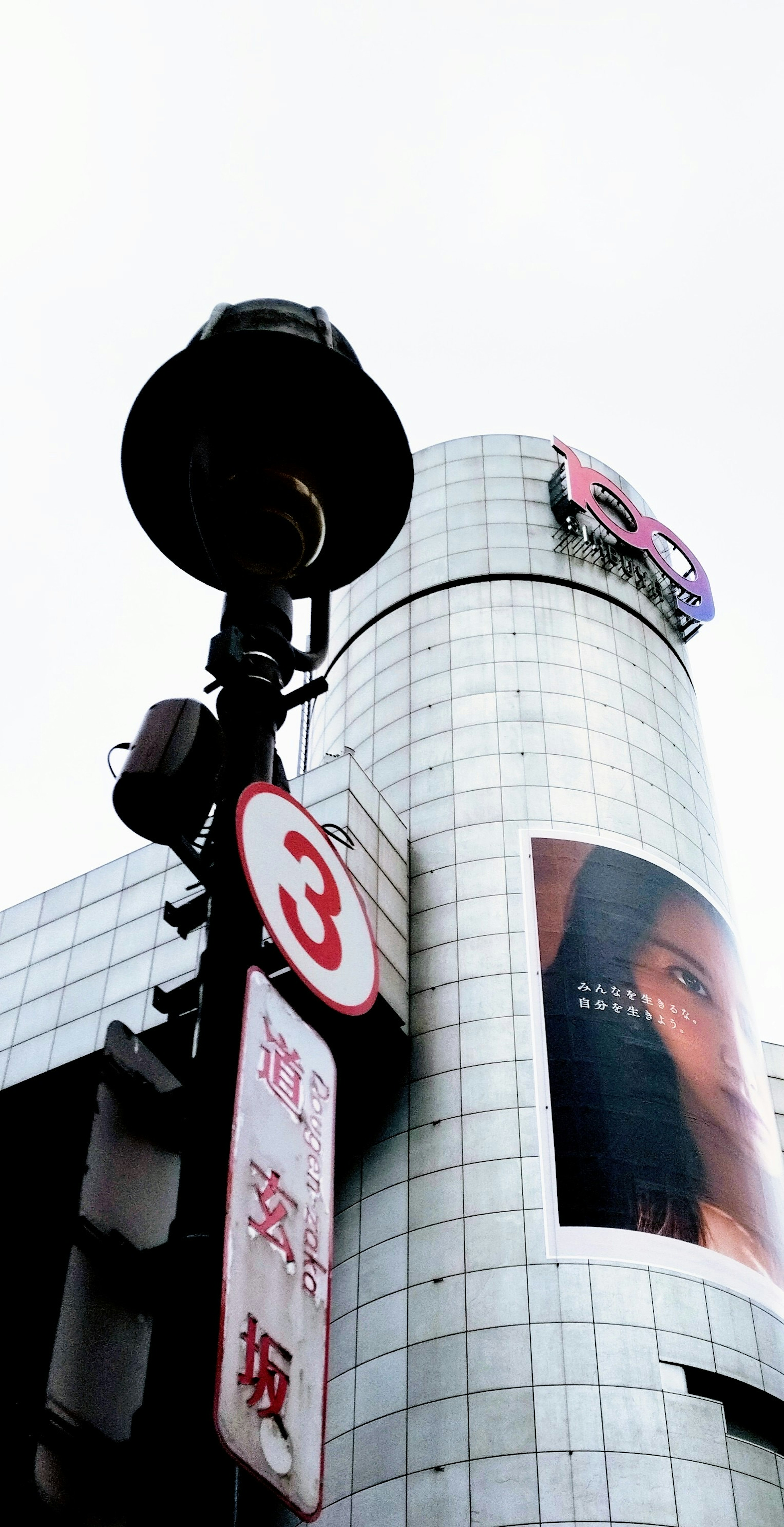 城市风景，银色建筑上有大型广告和交通信号灯