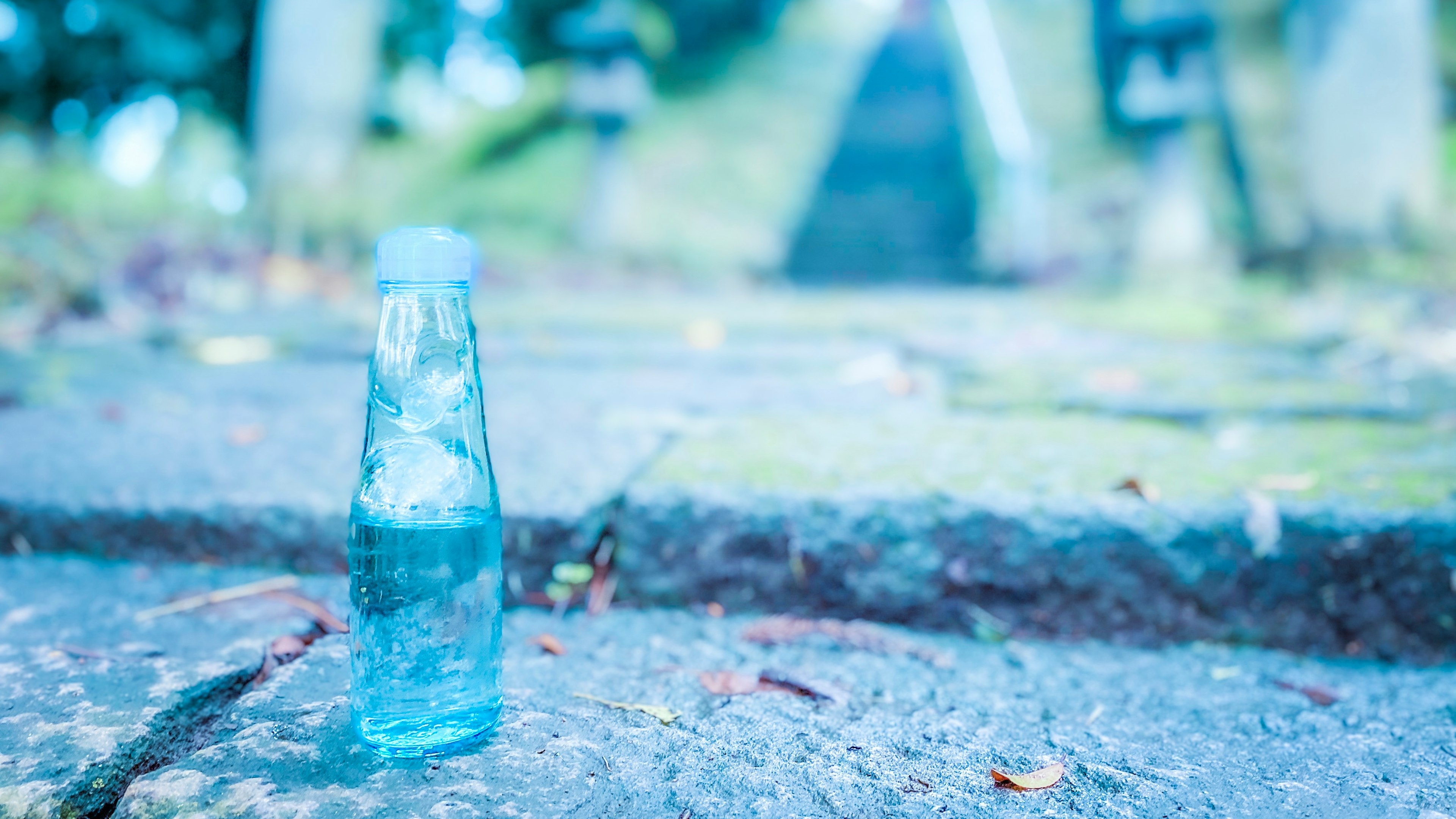 Una bottiglia d'acqua blu posata su un sentiero di pietra