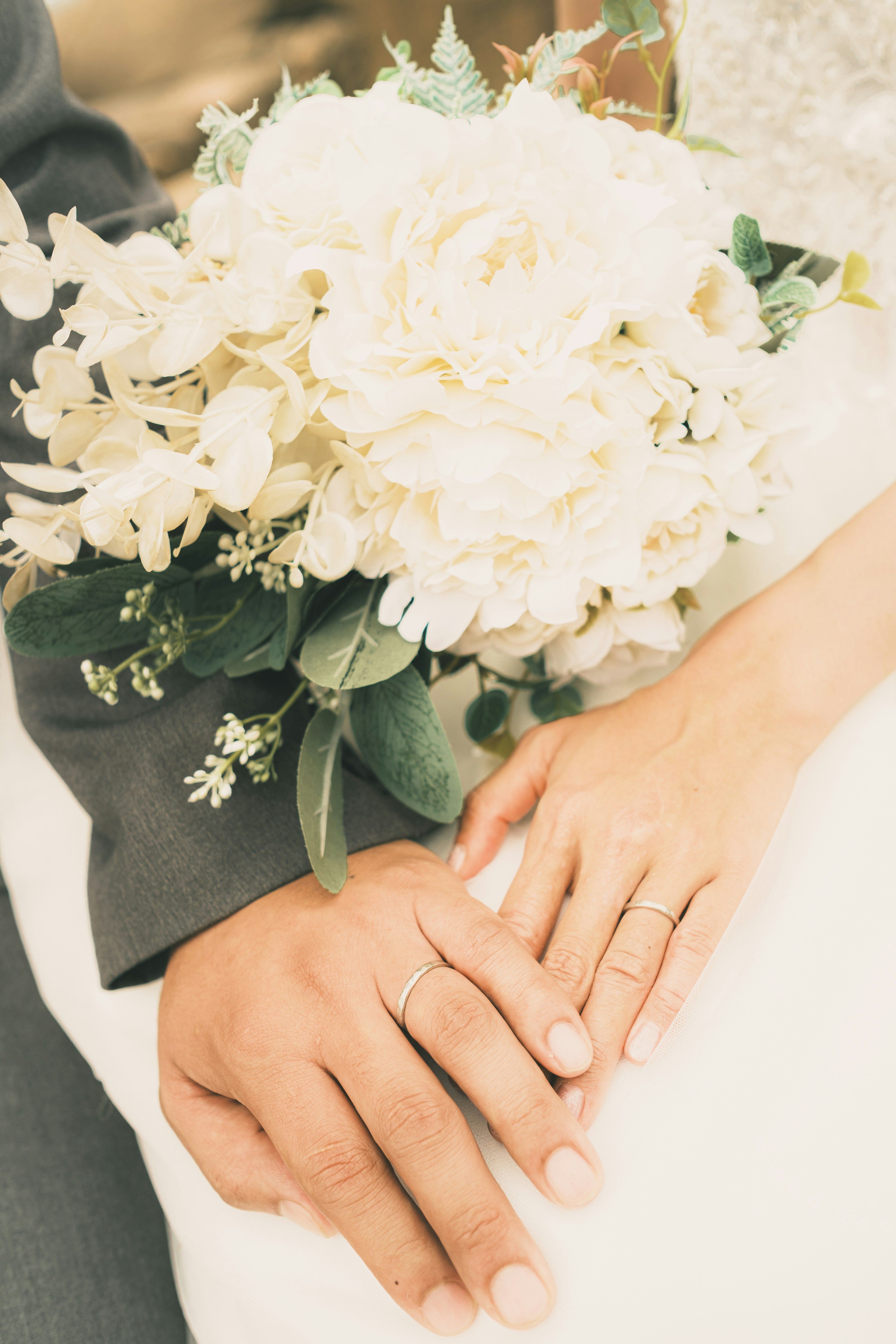 Close-up of couple's hands holding a wedding bouquet