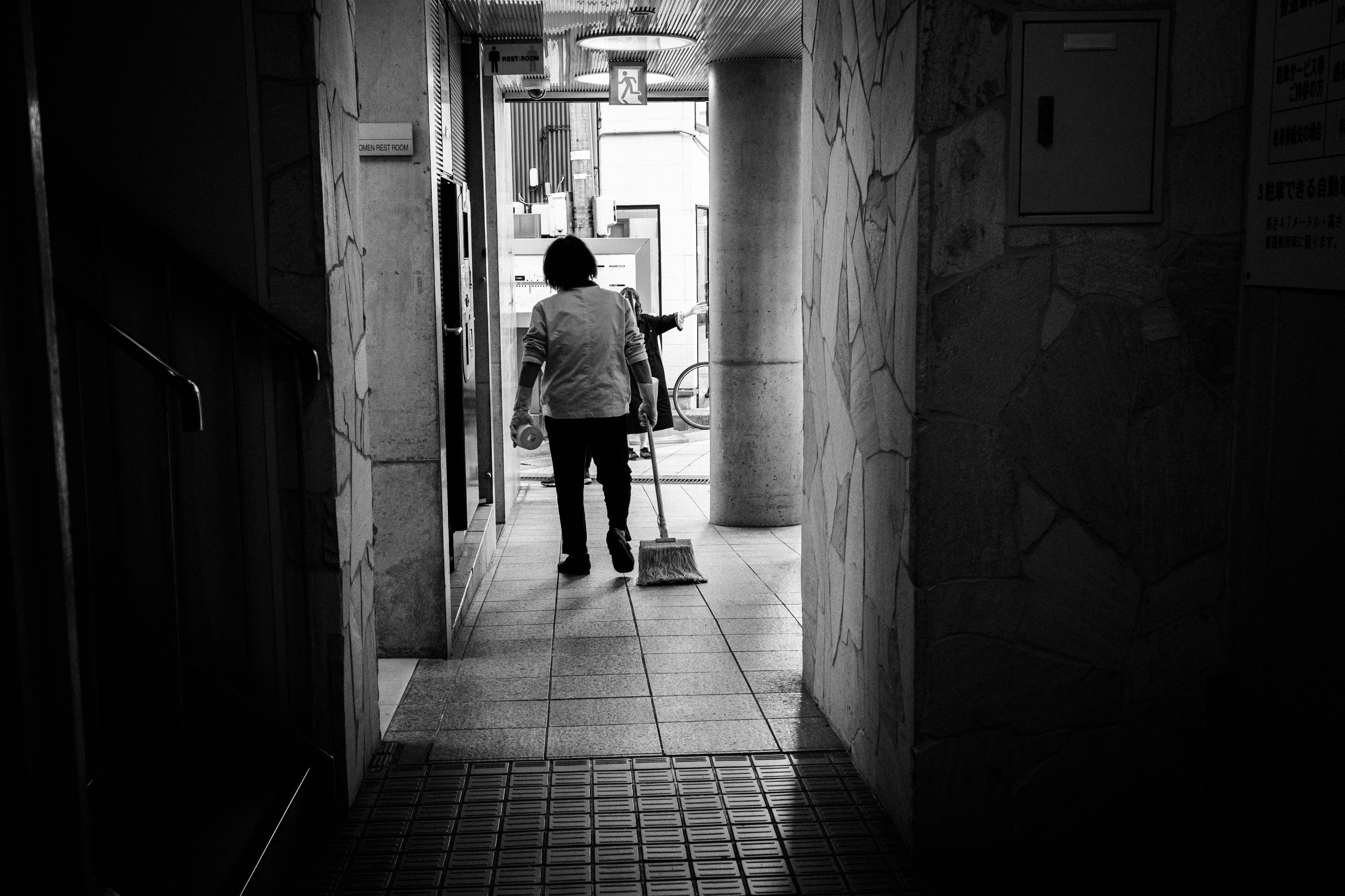 Person sweeping in a dimly lit hallway