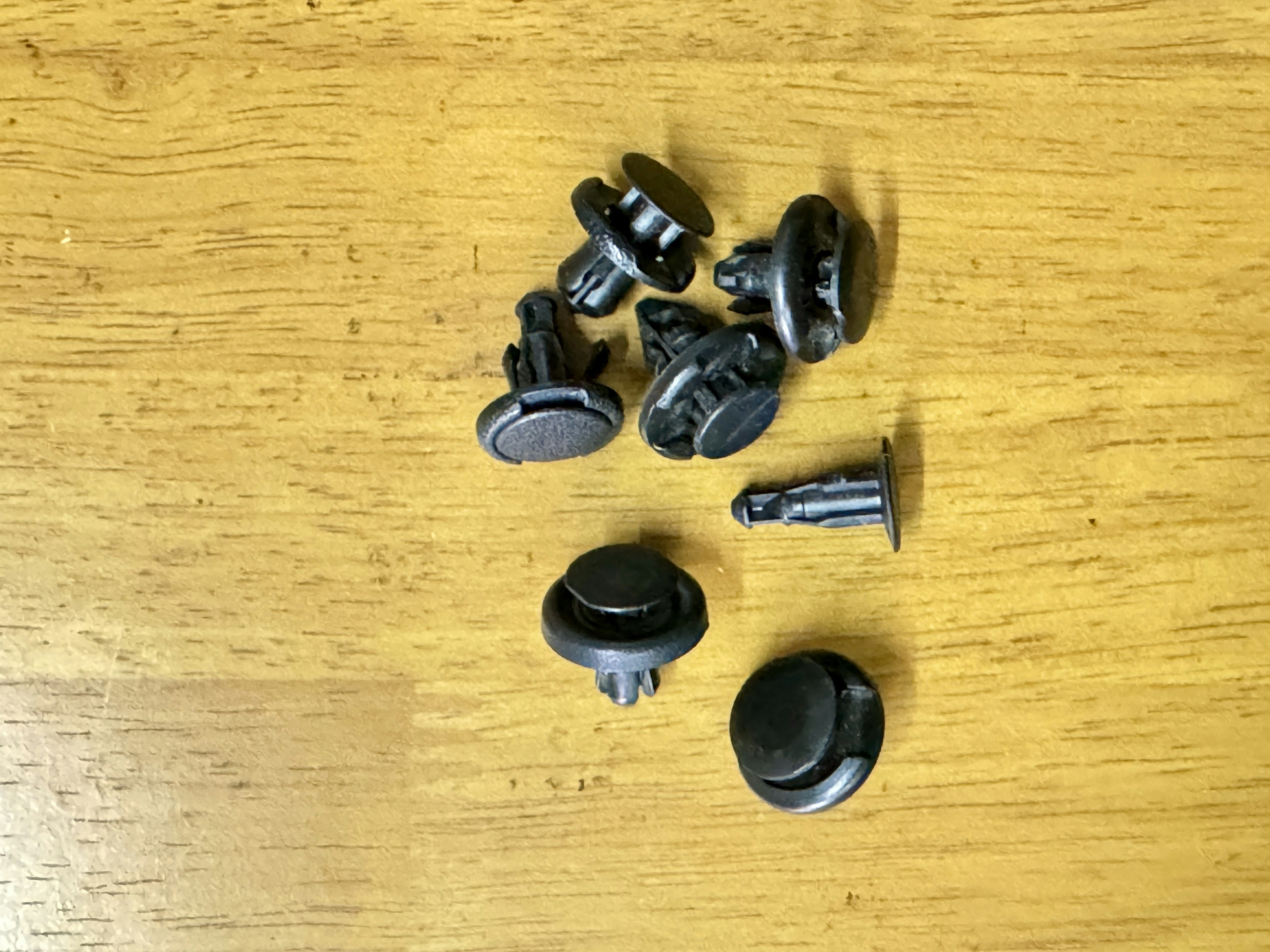 Various black buttons and clips scattered on a wooden table