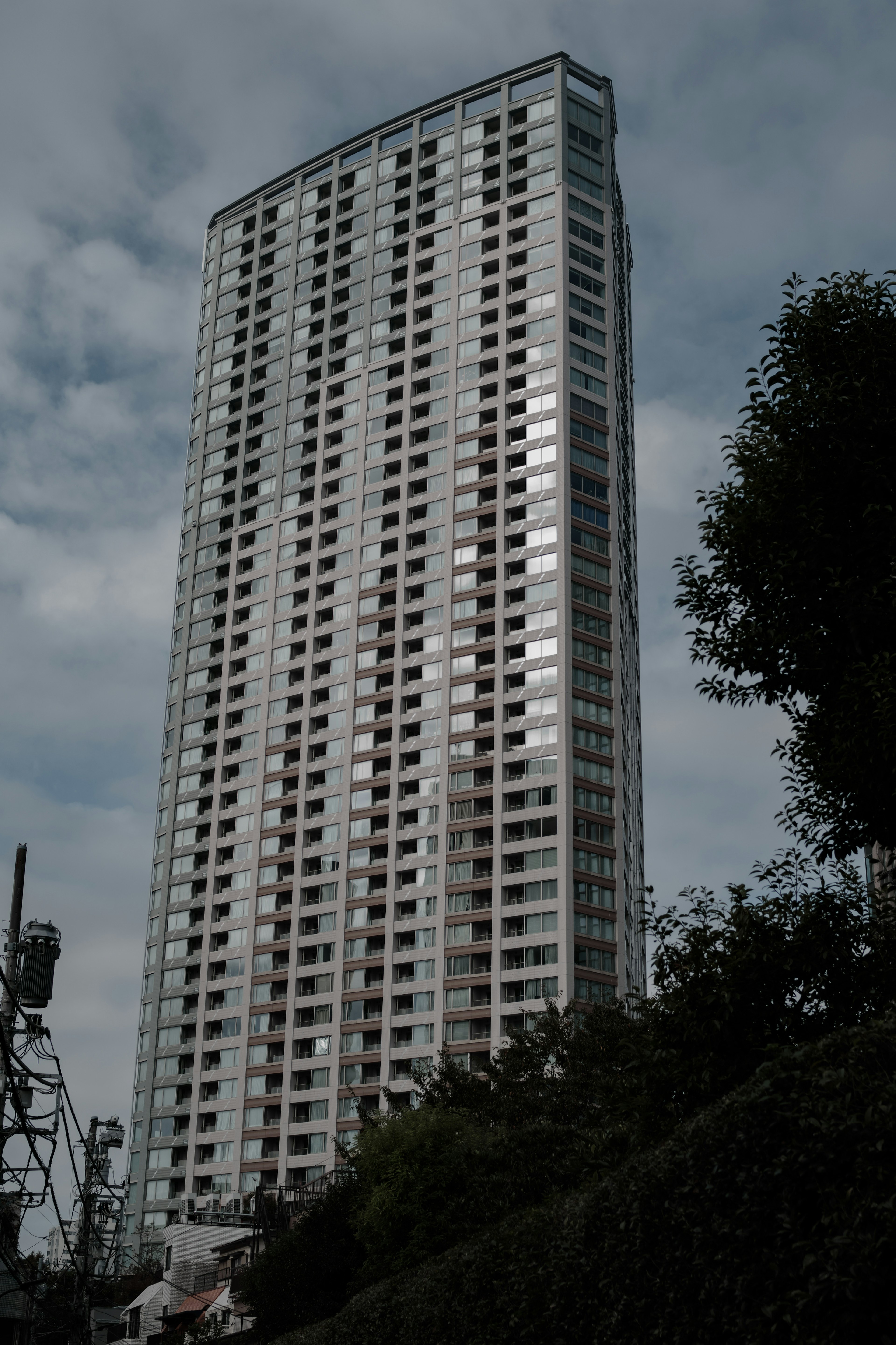 Immagine di un alto edificio con design moderno caratterizzato da numerose finestre e cielo nuvoloso