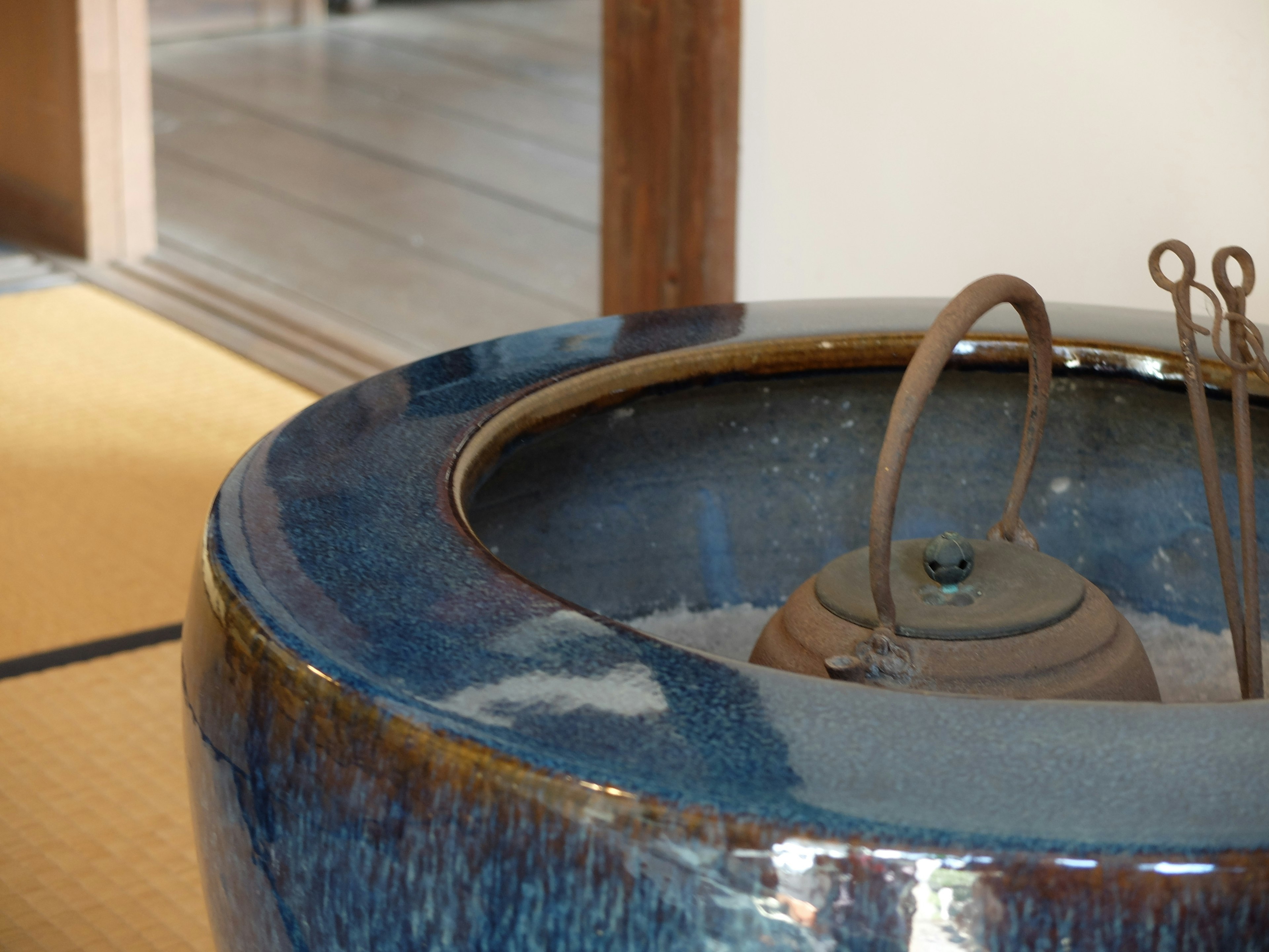 Blue ceramic irori with iron utensils in a traditional Japanese room