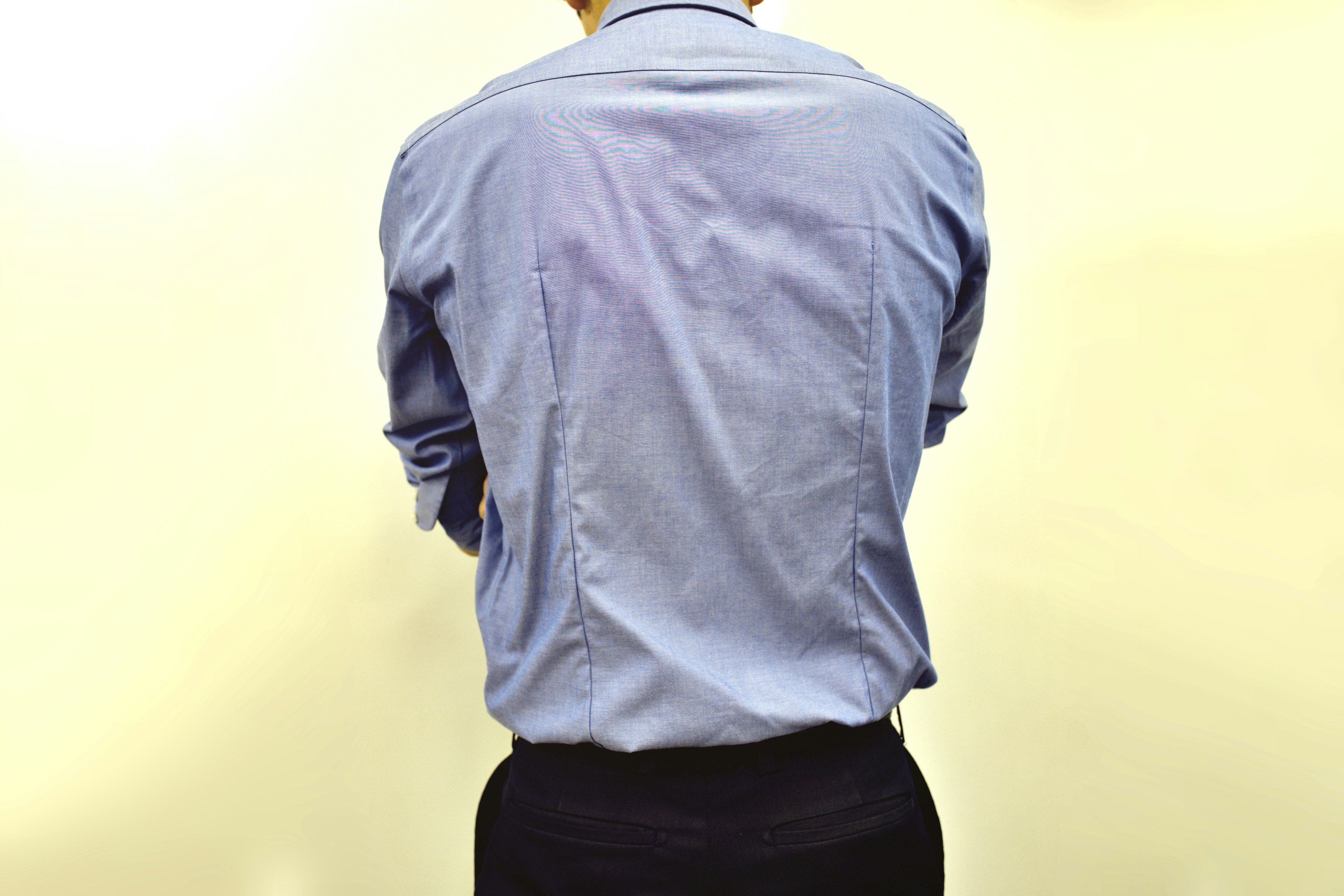 A man seen from behind wearing a blue shirt and black pants